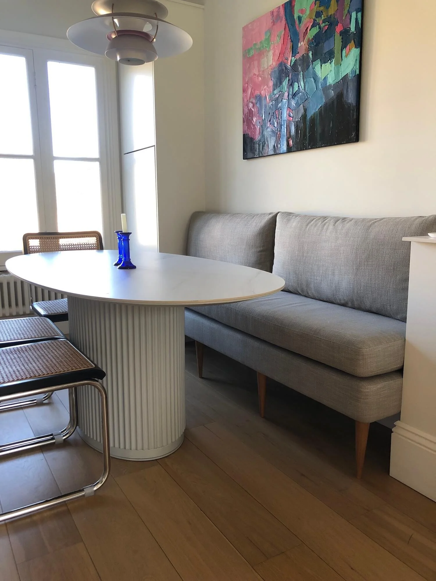 Grey banquette seating beside round dining table with fluted base