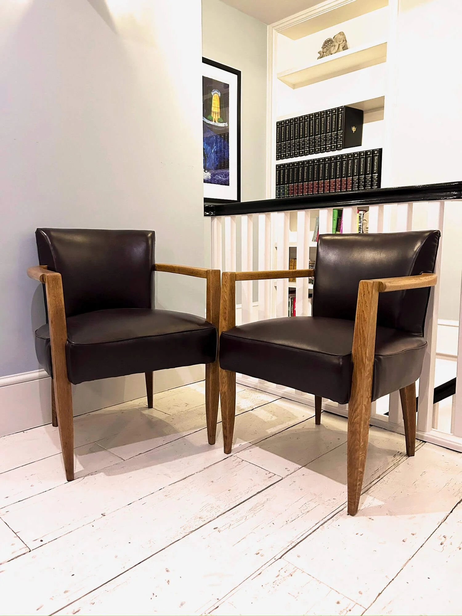 Two French bridge chairs upholstered in brown Italian leather with oak tapered legs on a white wooden floor