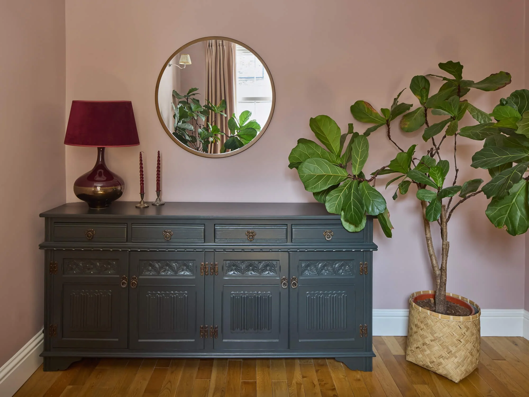 Painted sideboard with round mirror, fiddle-leaf fig and blush walls elegantly.