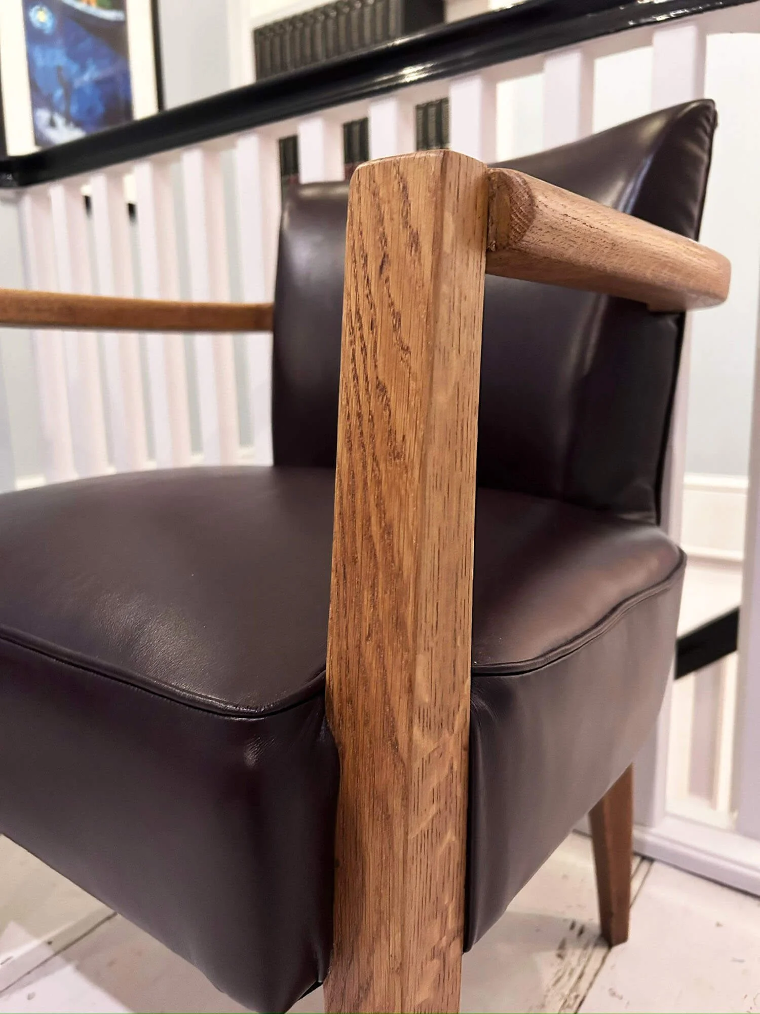 Close up of the oak leg and arm on a French bridge chair in brown leather