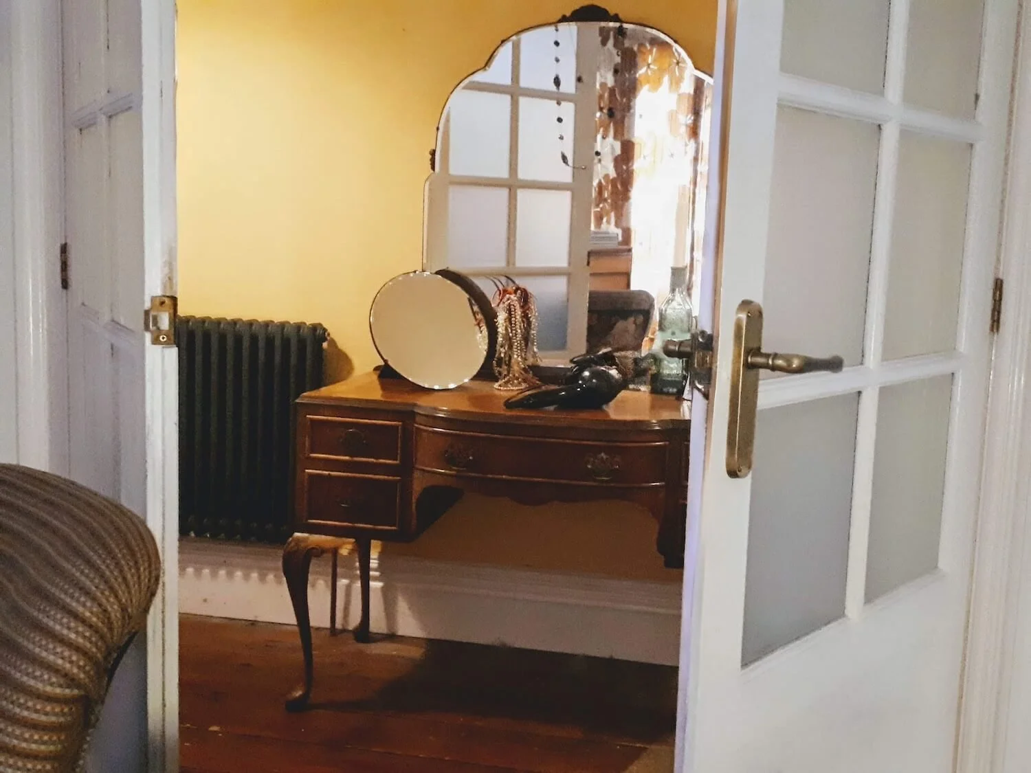 Hallway view into dressing table area with patterned curtains and wooden flooring