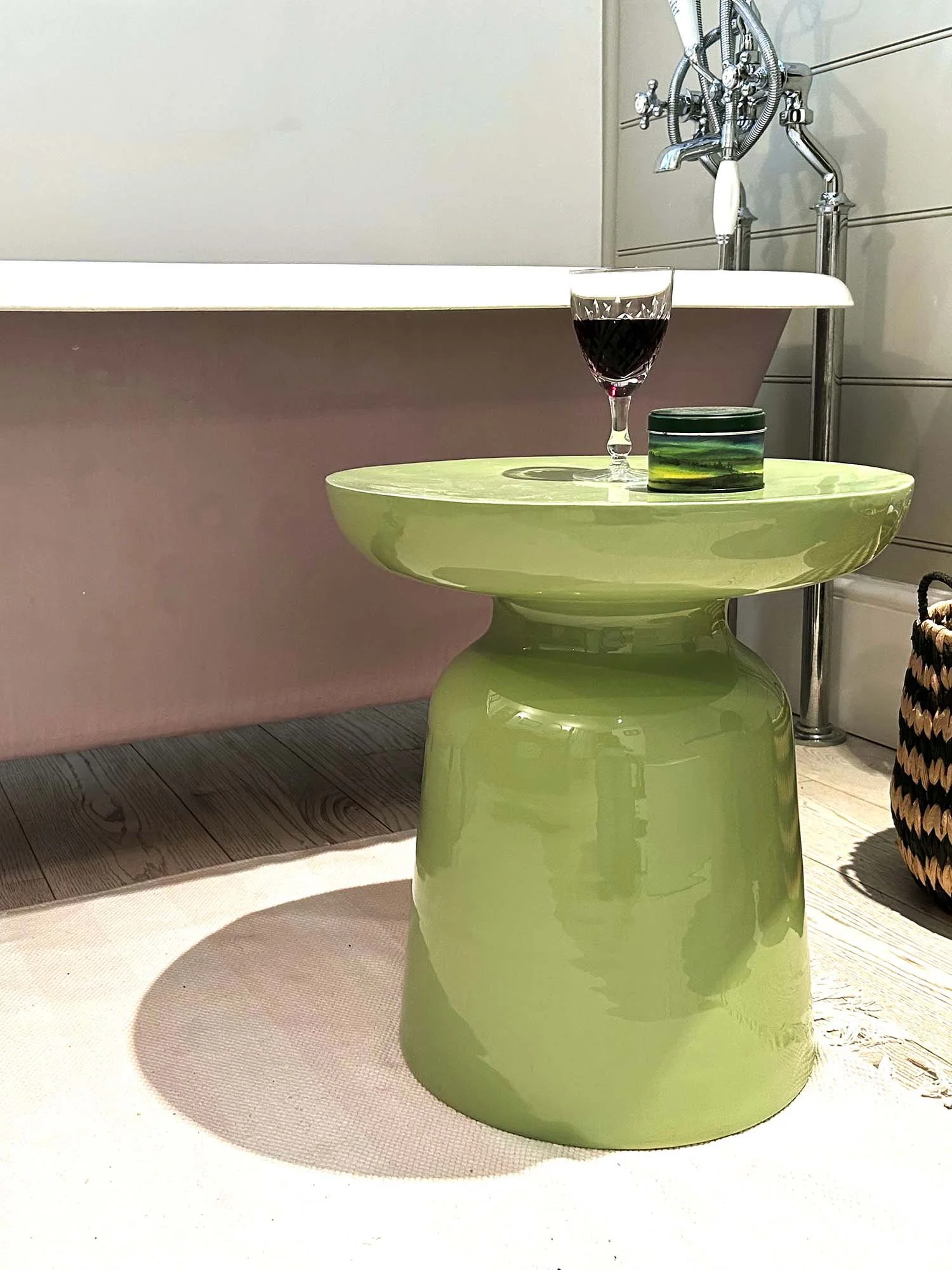 Matcha green metal side table with wine glass in light modern bathroom