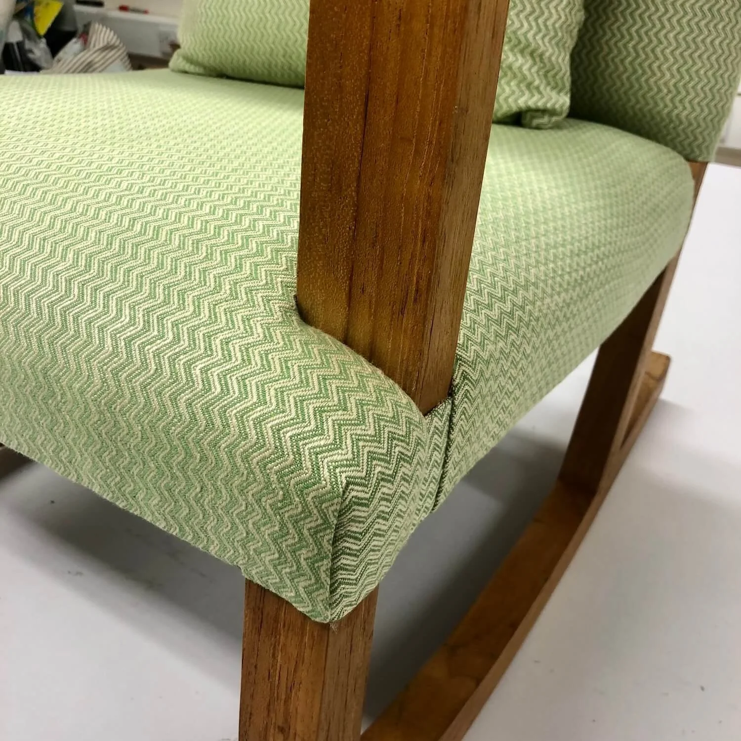 Detail of green contemporary chair showing new upholstery and wood frame
