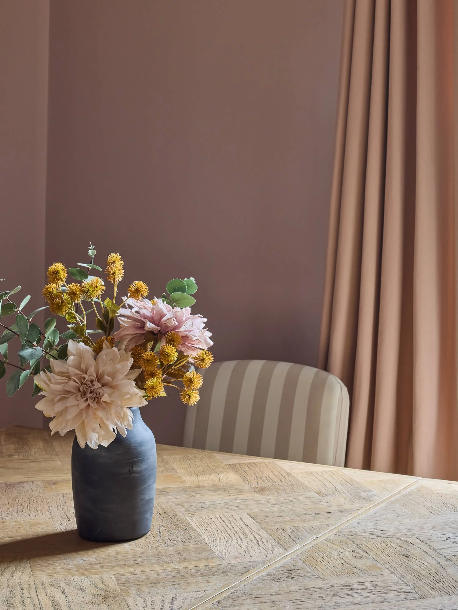Bespoke blush curtains framing elegant dining table with seasonal floral arrangement indoors.