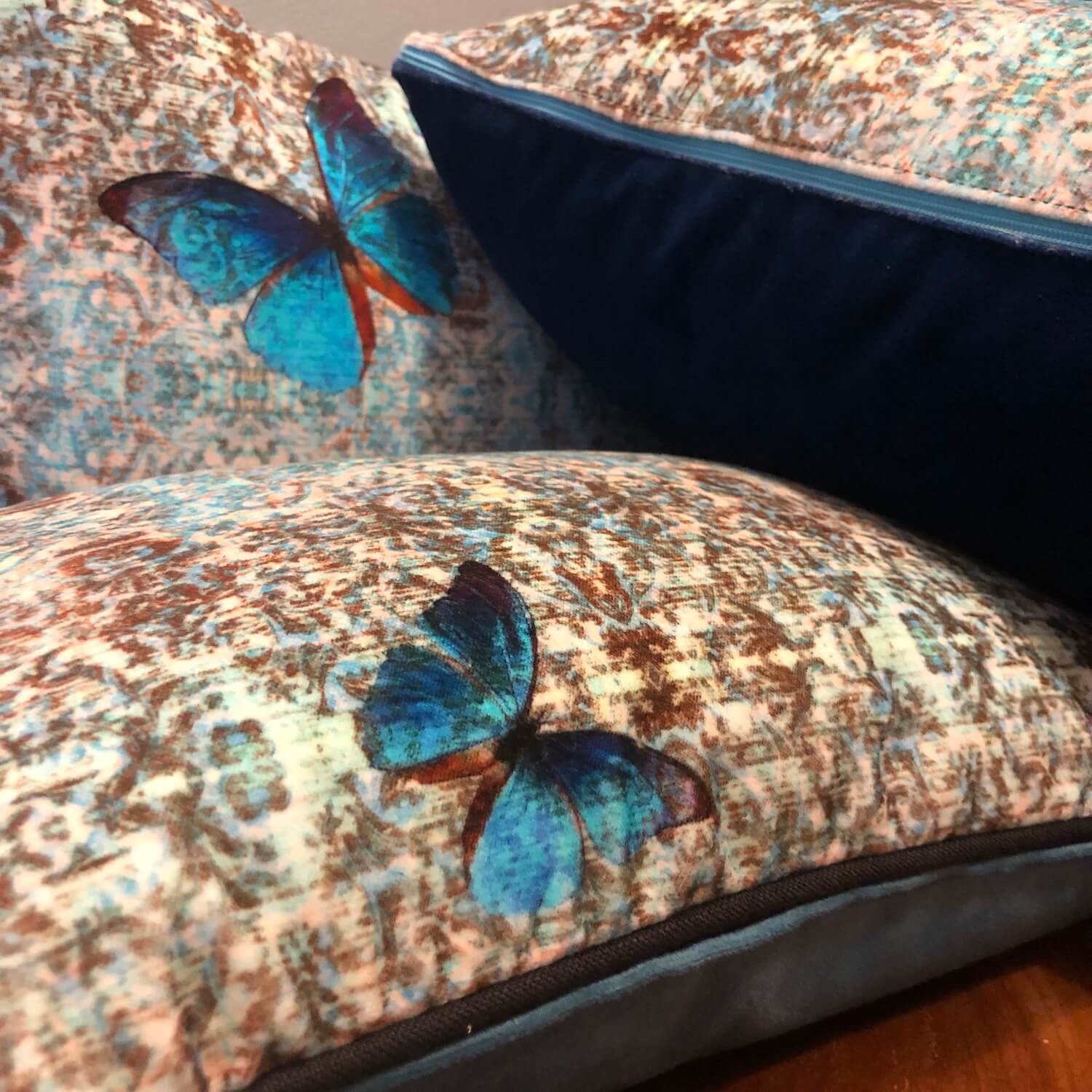 Butterfly patterned velvet cushion with rich blue accents