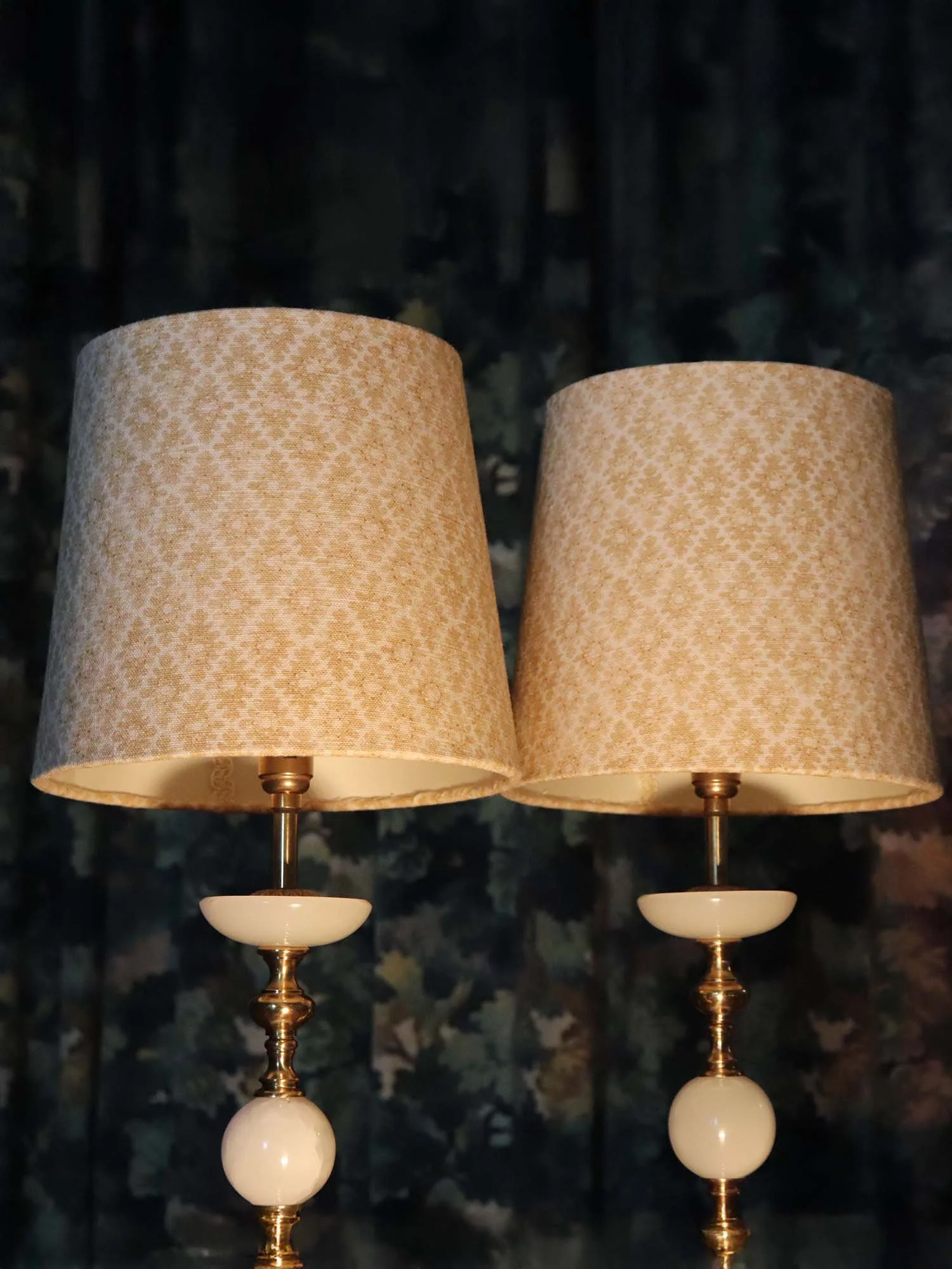 Pair of patterned lampshades glowing warmly in dark room