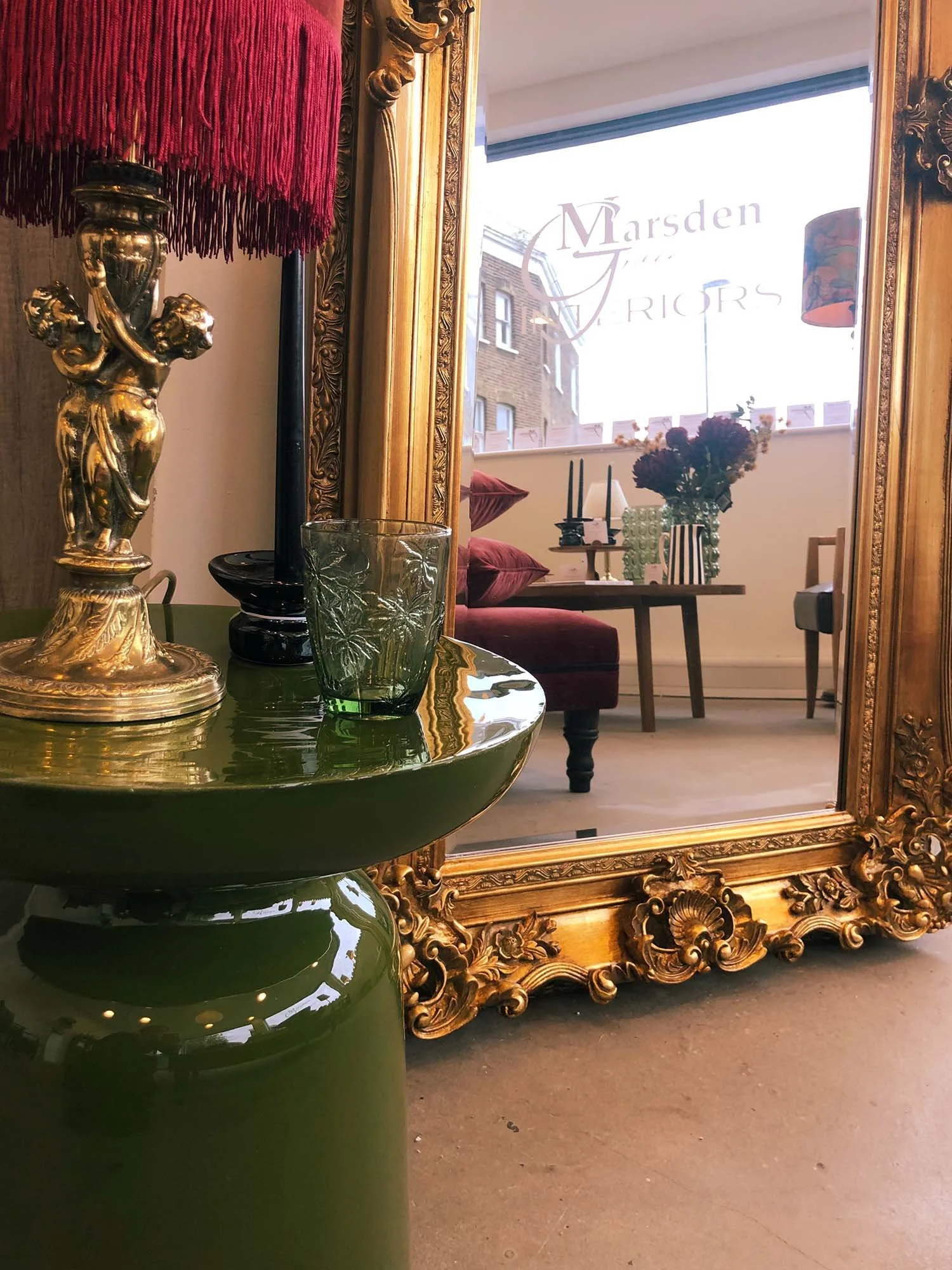 Antique gold mirror styled with green metal table decorative glassware and lamp