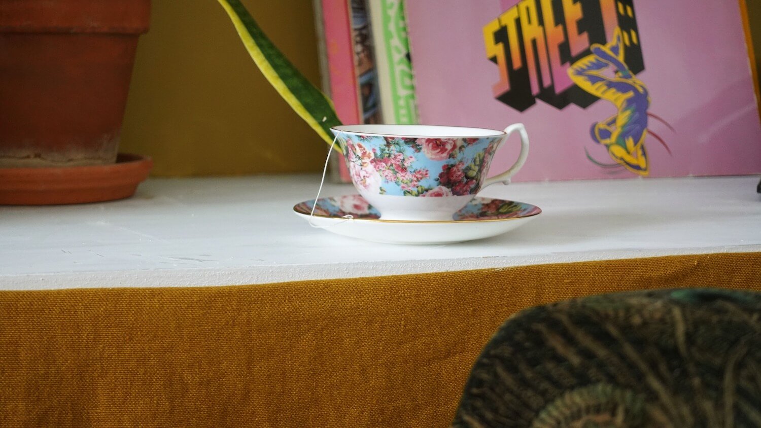 Close-up of shelf with decorative floral china teacup and saucer edge with pink trim detailing