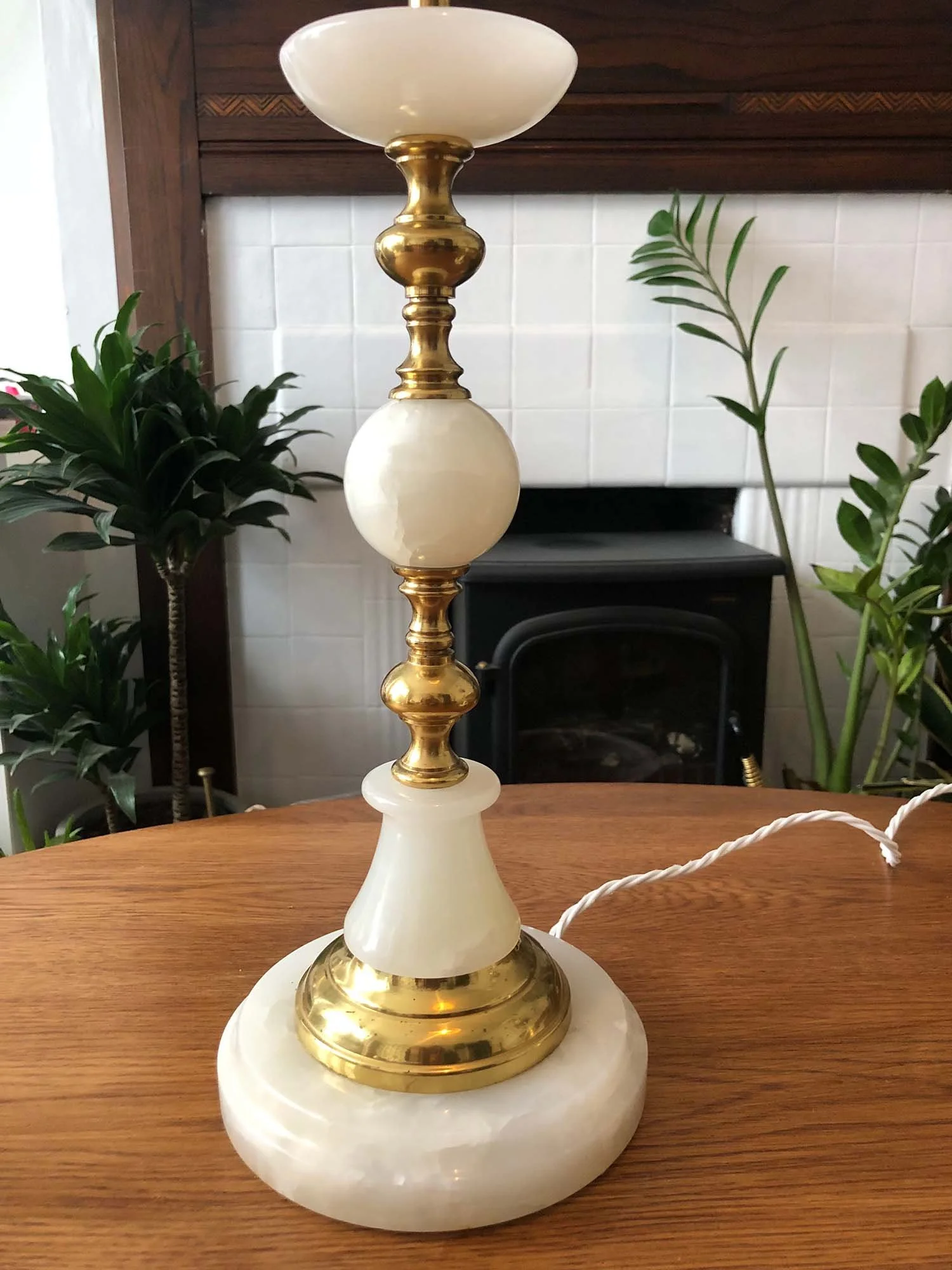Vintage marble lamp with brass detailing and round base beside plants