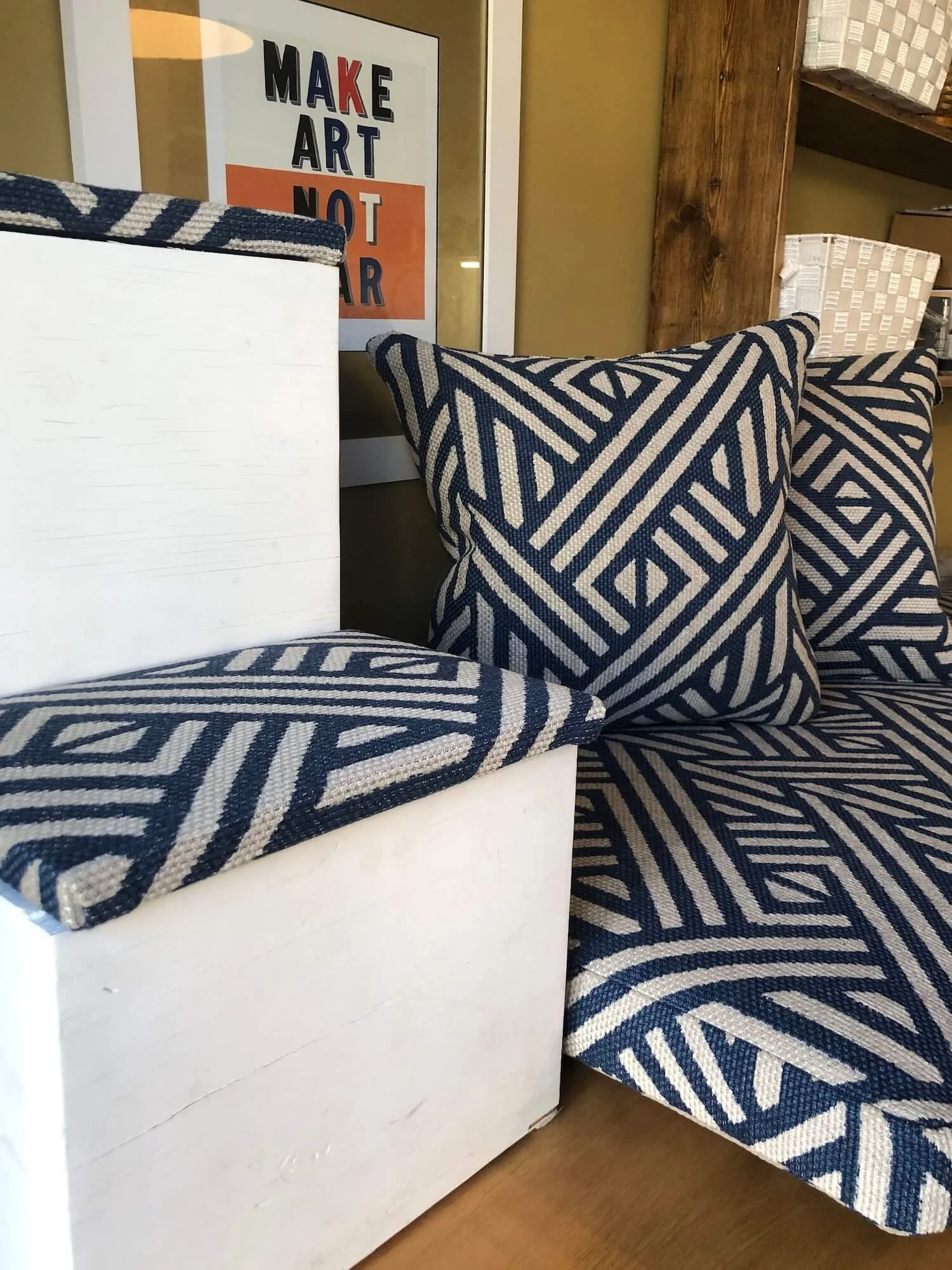Navy blue window seat with matching cushions and decorative pillowsBlue and white geometric patterned bench cushions stacked on white bench