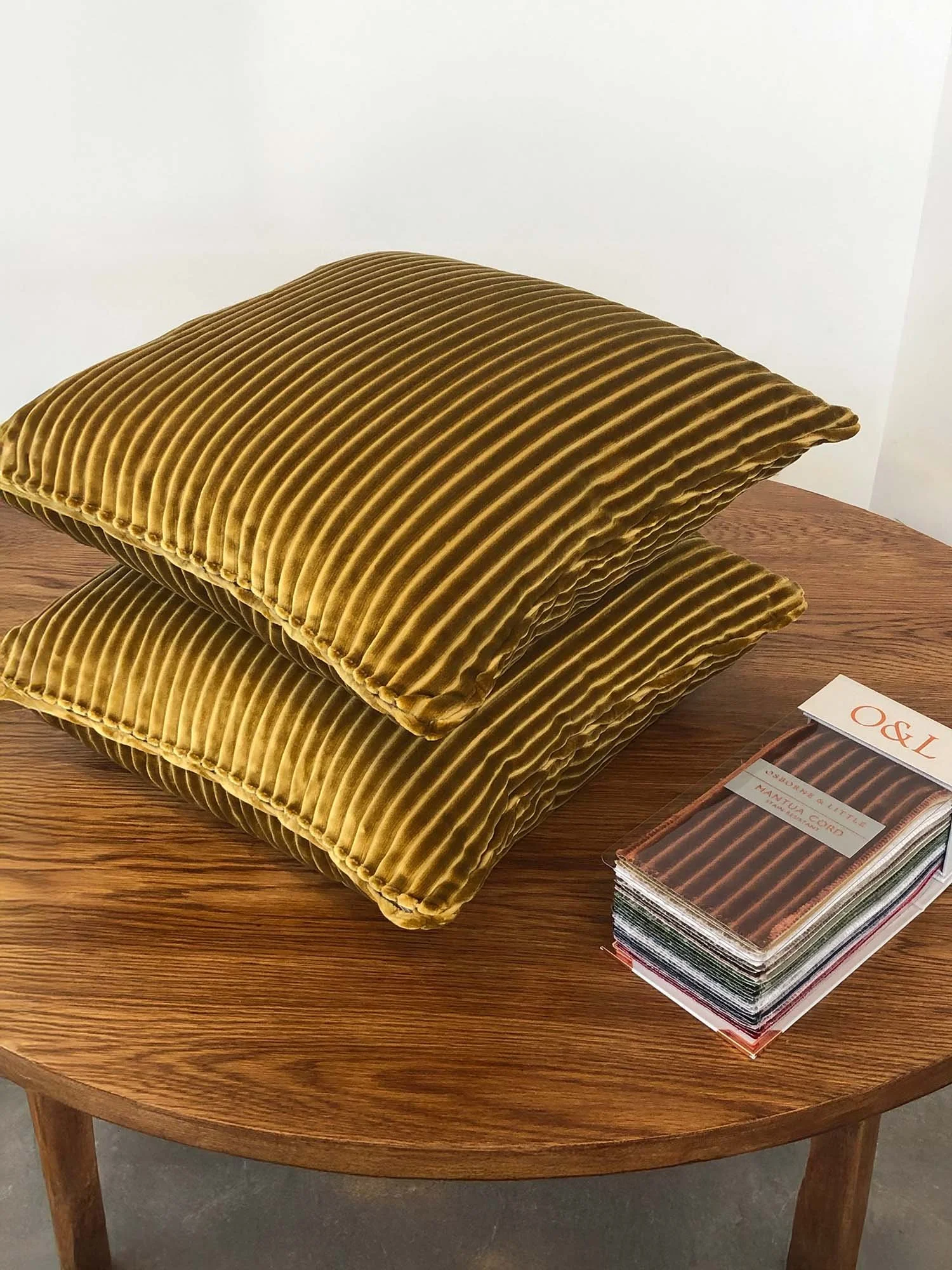 Stack of Mantua cord cushions in caramel velvet cord displayed on wooden table