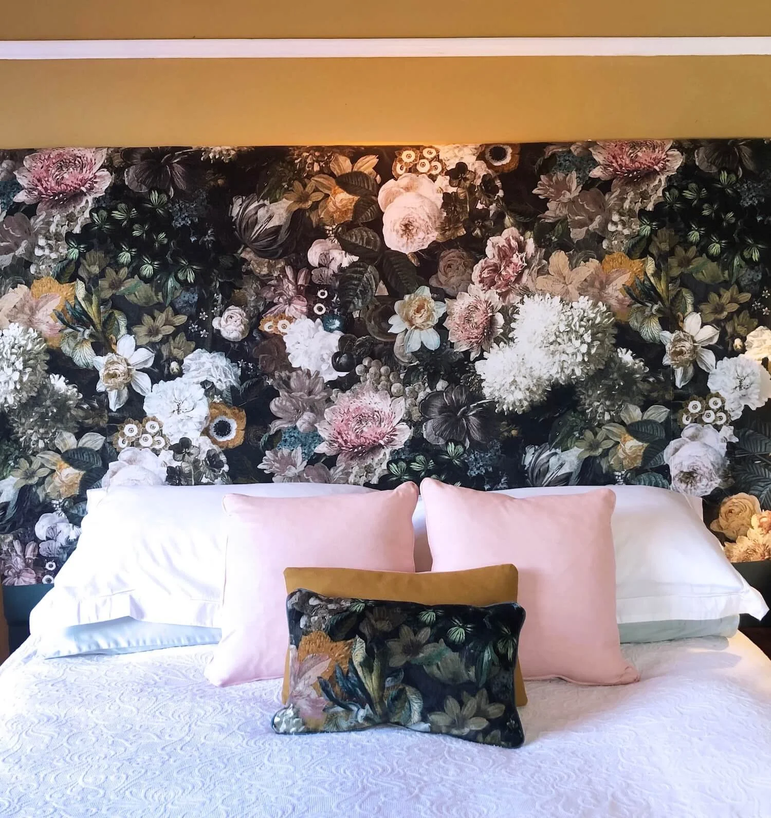 Bedroom featuring dramatic floral headboard and blue and pink cushions
