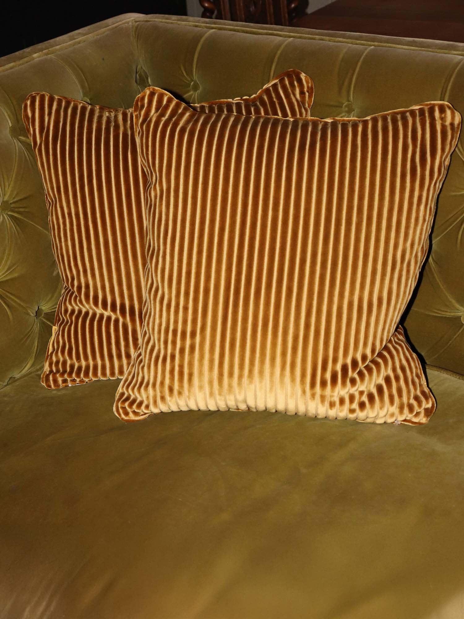 Pair of Mantua cord cushions in caramel velvet cord on green velvet sofa