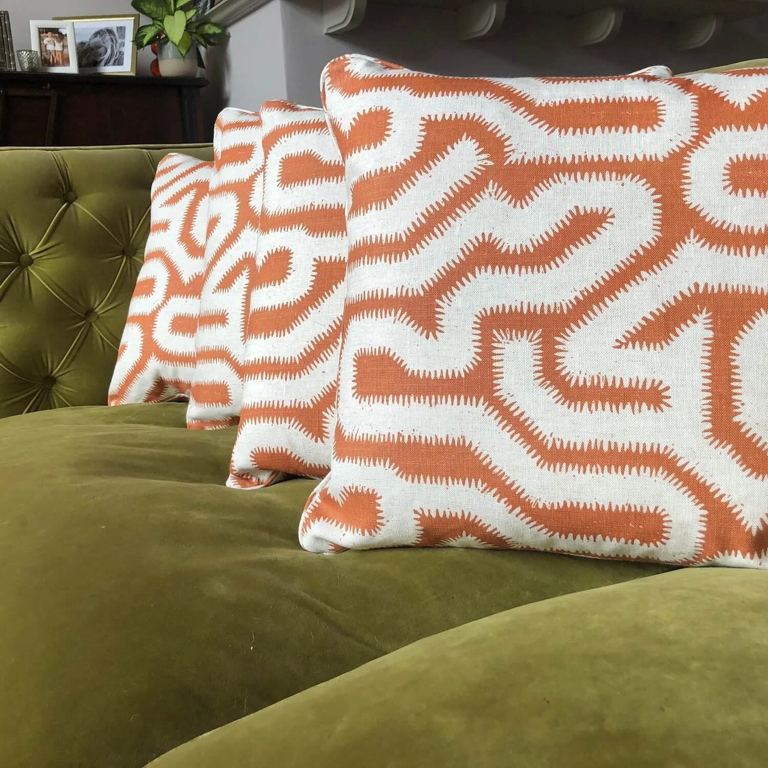 Bold patterned cushions on olive green velvet seat