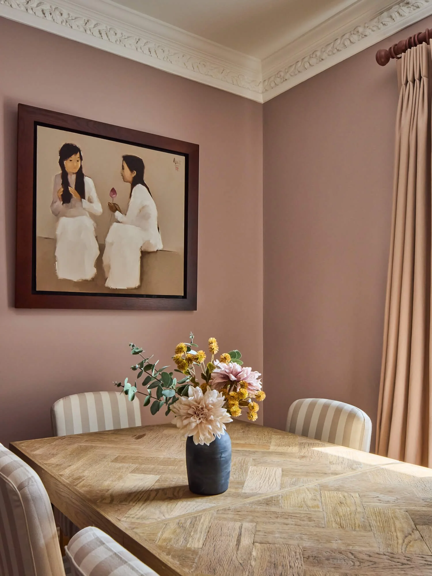 South London dining room with blush walls, bespoke curtains and artwork displayed.