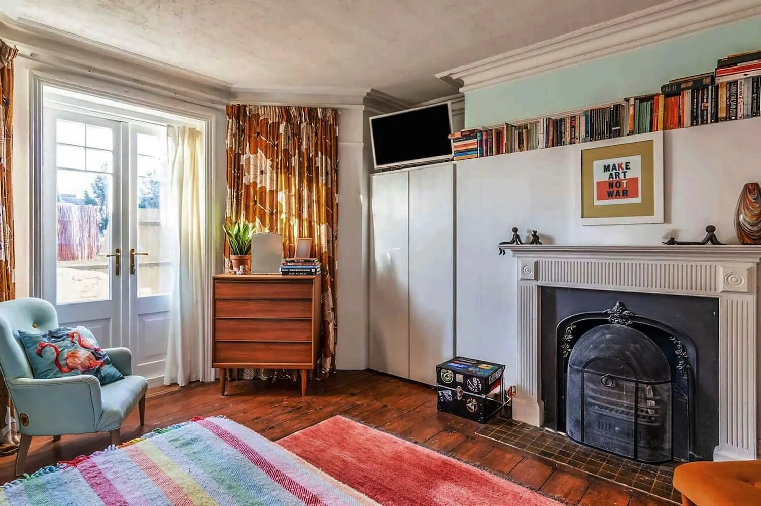Bedroom room with vintage fireplace, colourful rug and 1970s-inspired décor