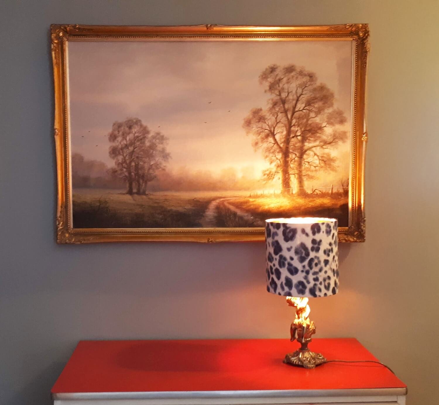 Console table with framed landscape painting and patterned lamp