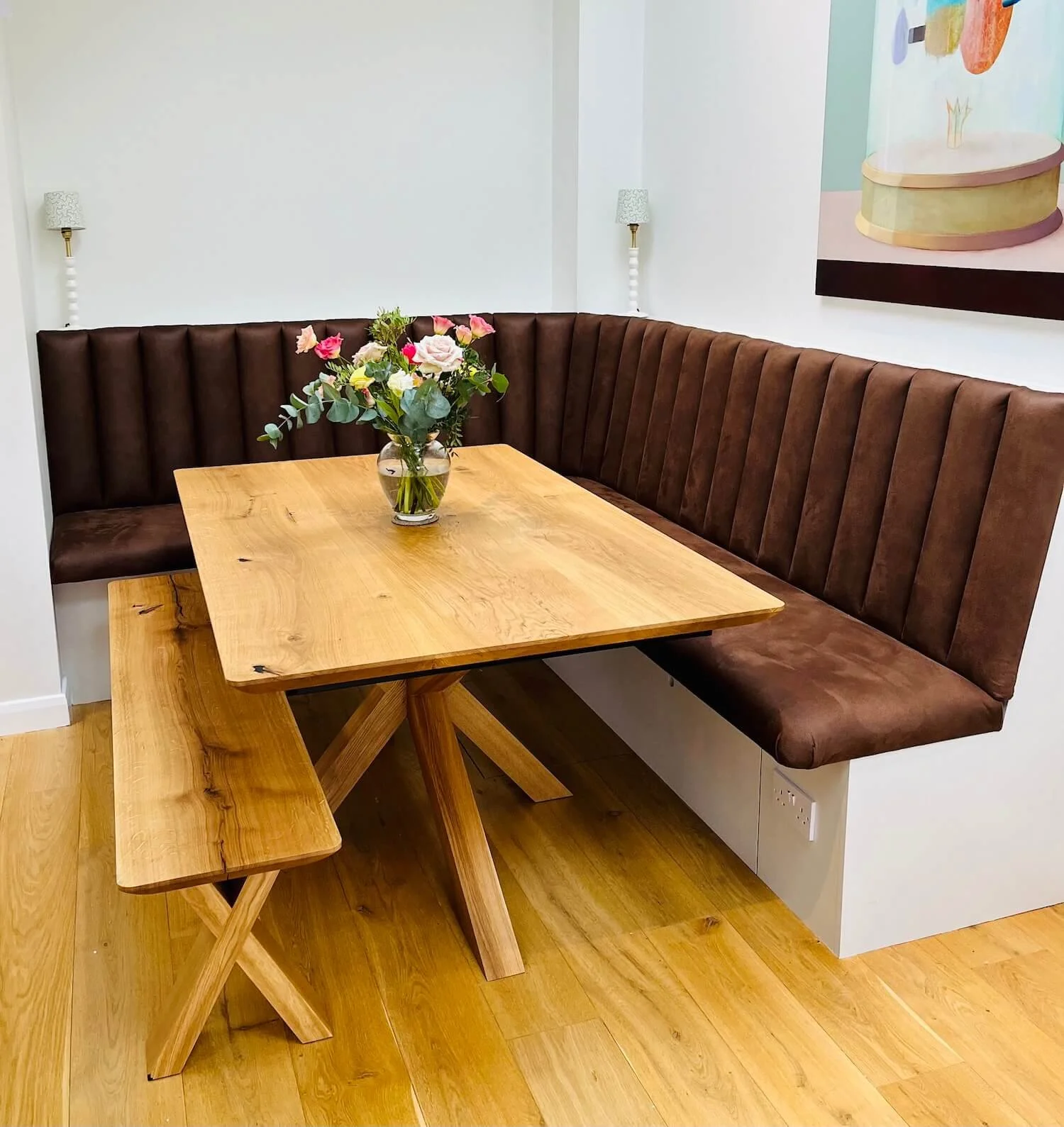 Corner banquette seating in wood-panelled dining nook with round wooden table