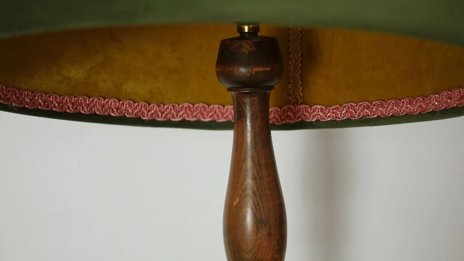 Close-up of side table with wooden lamp base and decorative pink shade trim detail