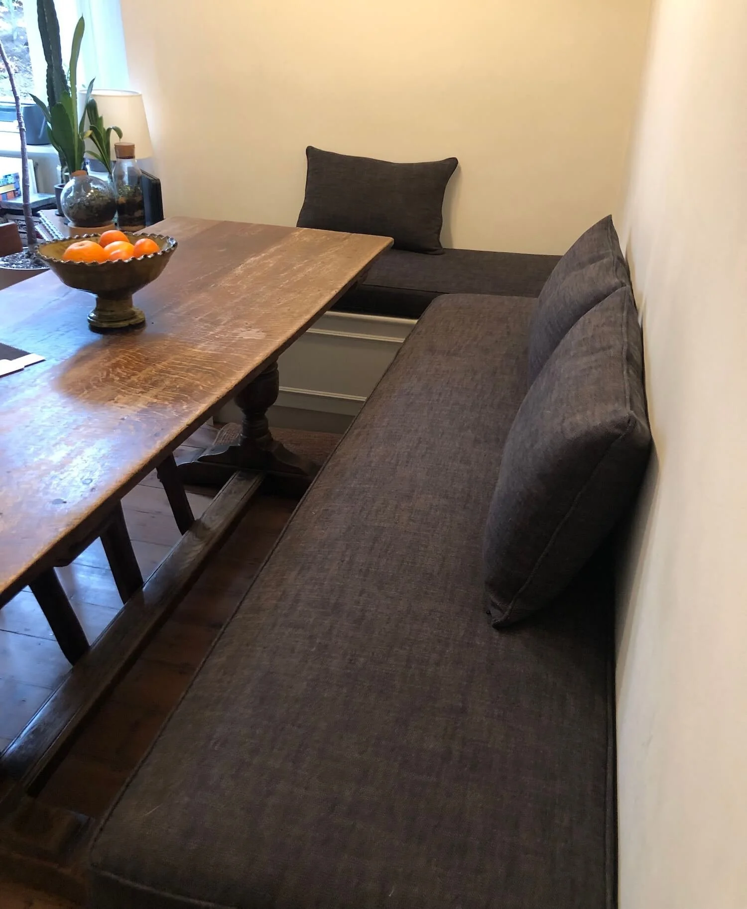 Dining bench with charcoal upholstered seat cushions and matching bolsters