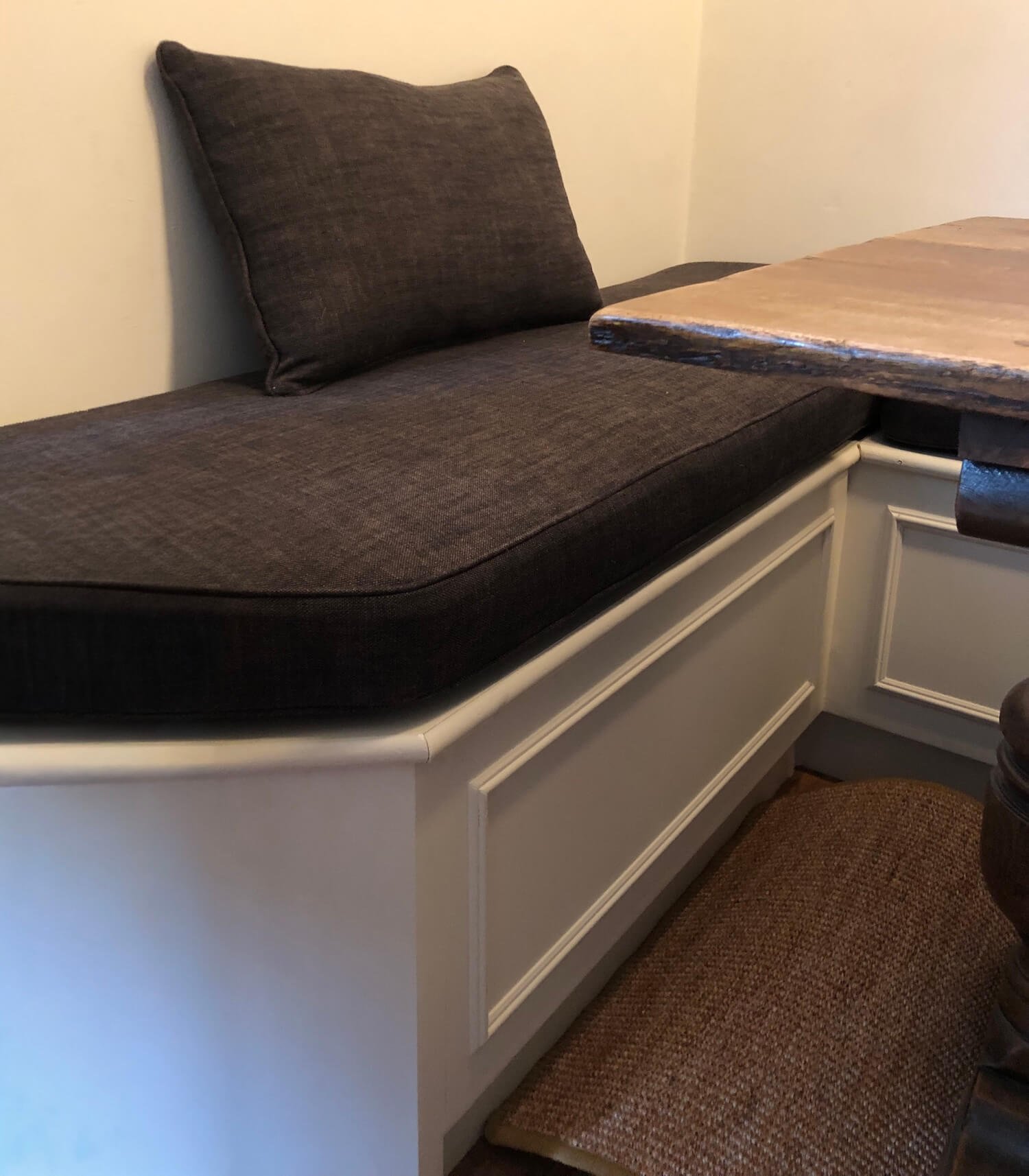 Corner bench seat with dark grey cushions and white built-in base