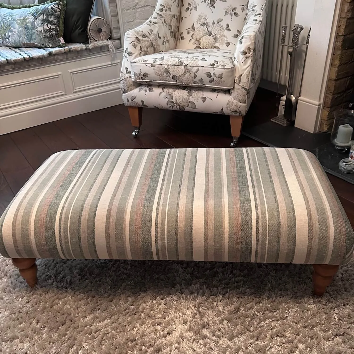 Striped ottoman with traditional wooden legs after reupholstery