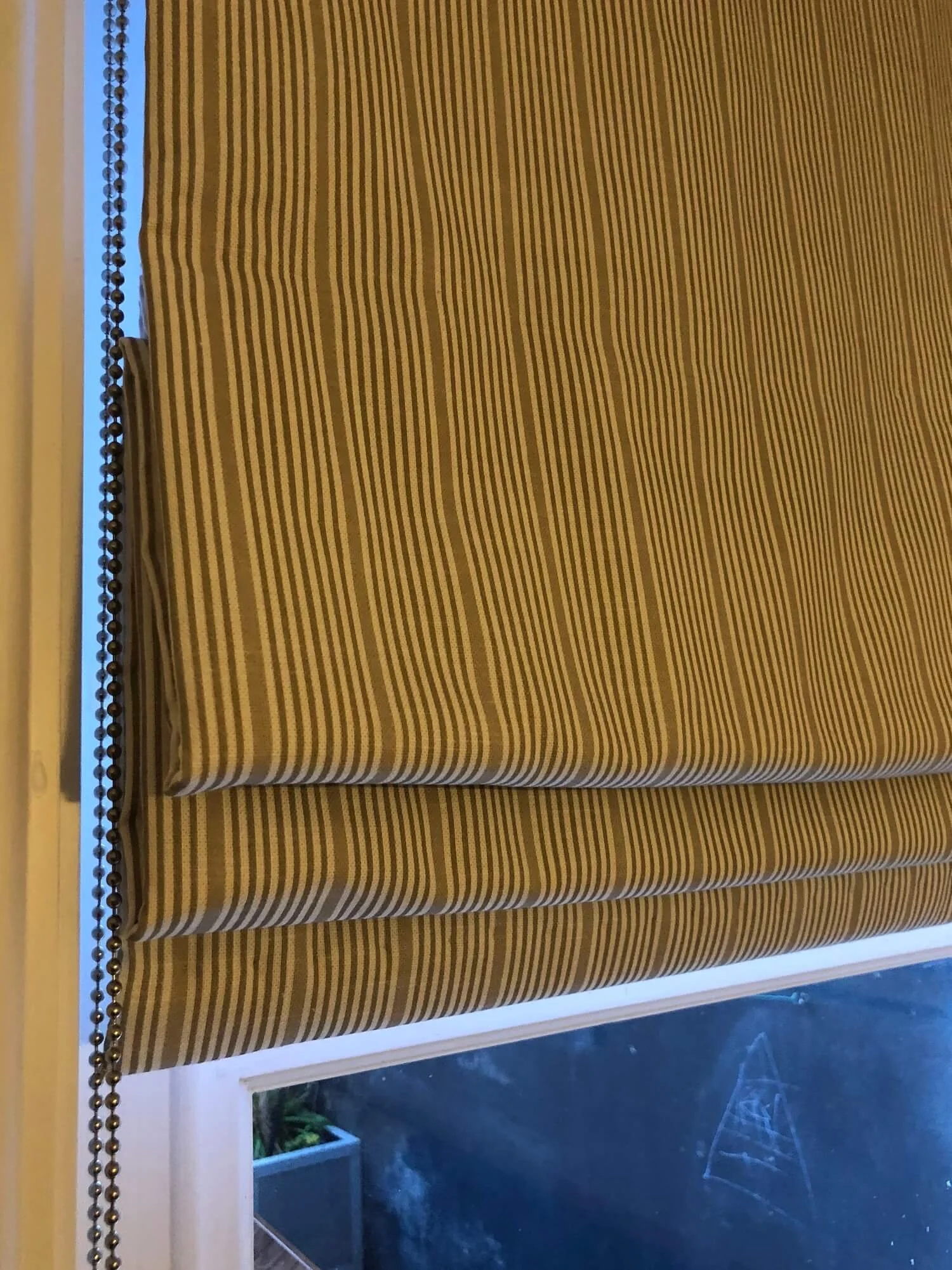 Pleated Roman blind in textured natural fabric in living room window