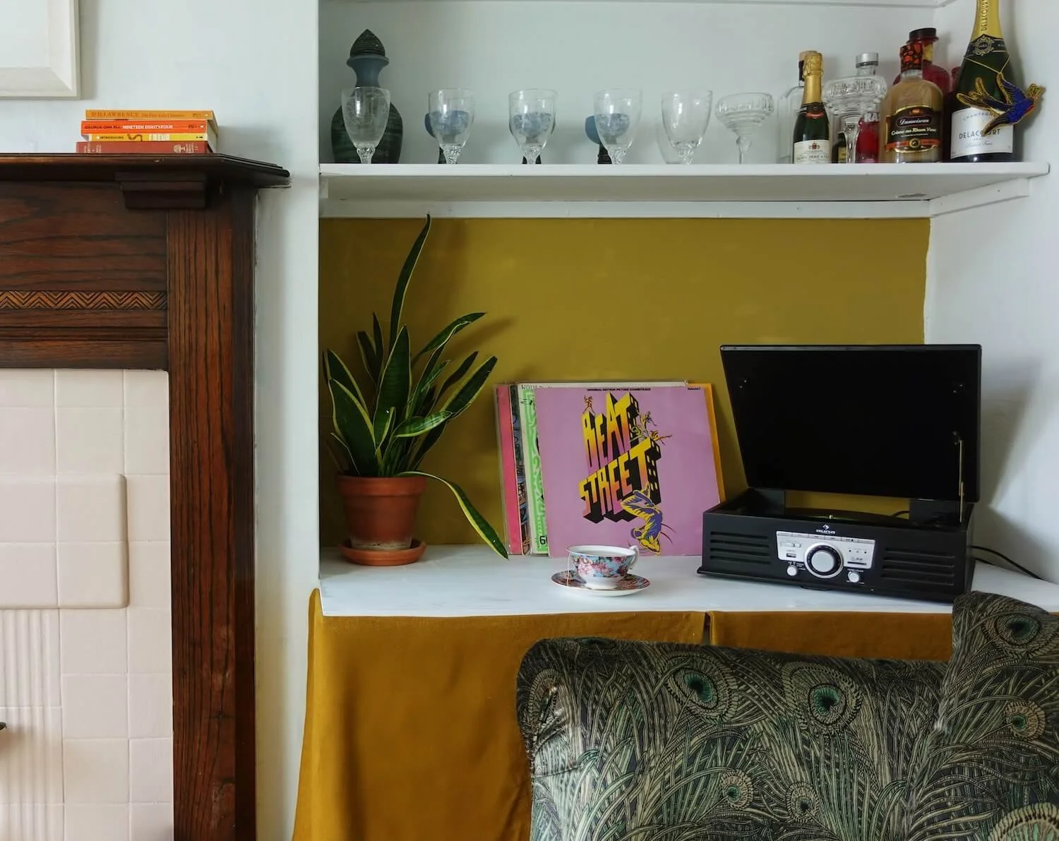 Styled shelving alcove with barware, vinyl records and olive-green chair