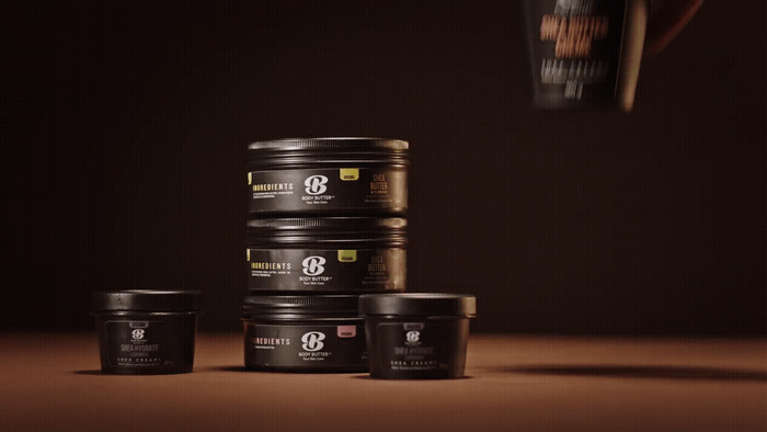 Stacked containers of body butter and skincare products on a dark background.