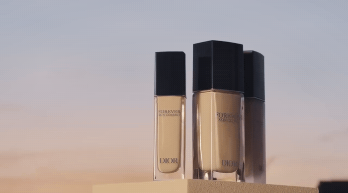 Three bottles of Dior Forever Skin Correct concealer on a flat surface against a gradient sky background.