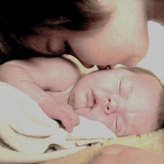 A young child kisses the cheek of an infant