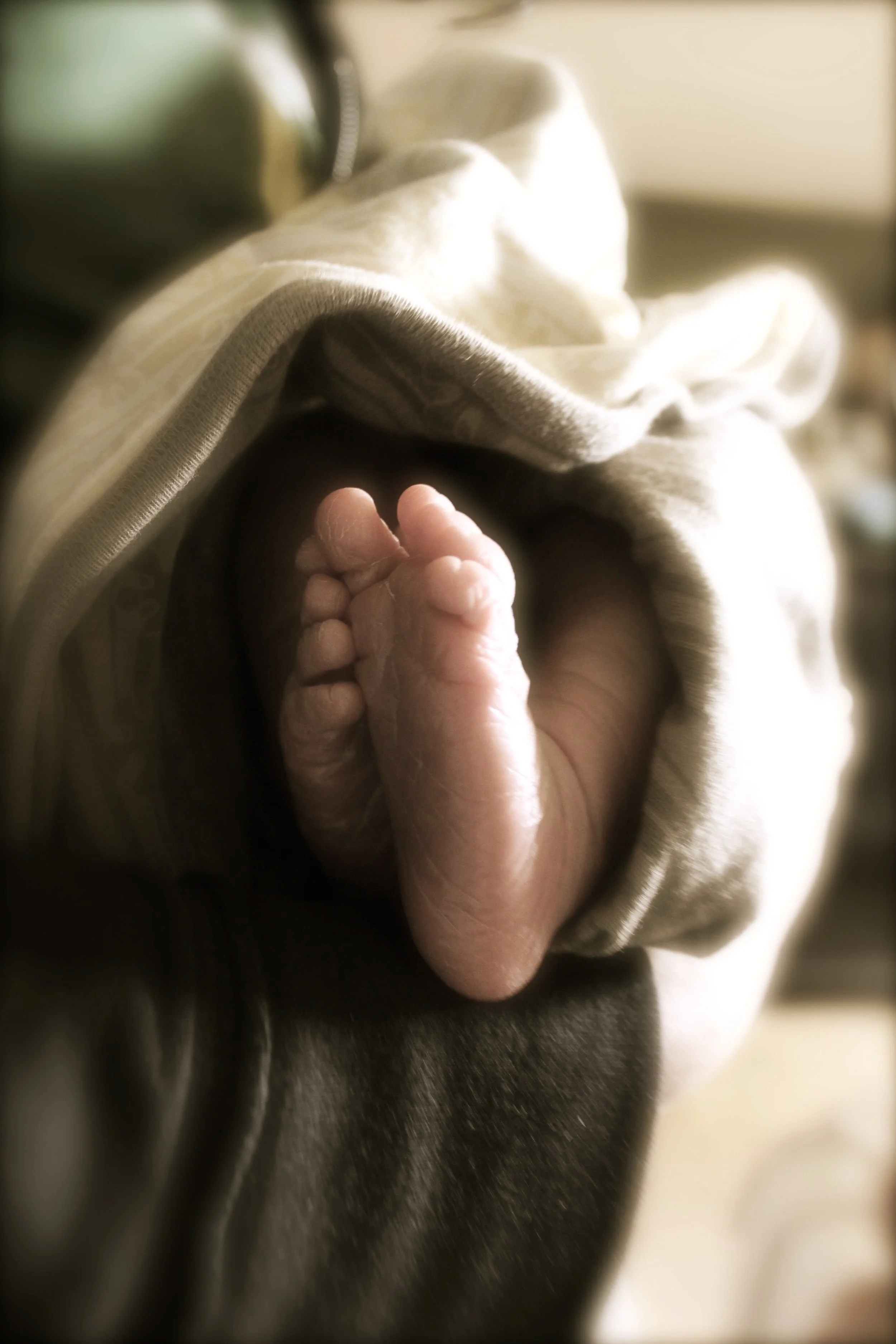 A swaddled baby's feet sticking out from blankets