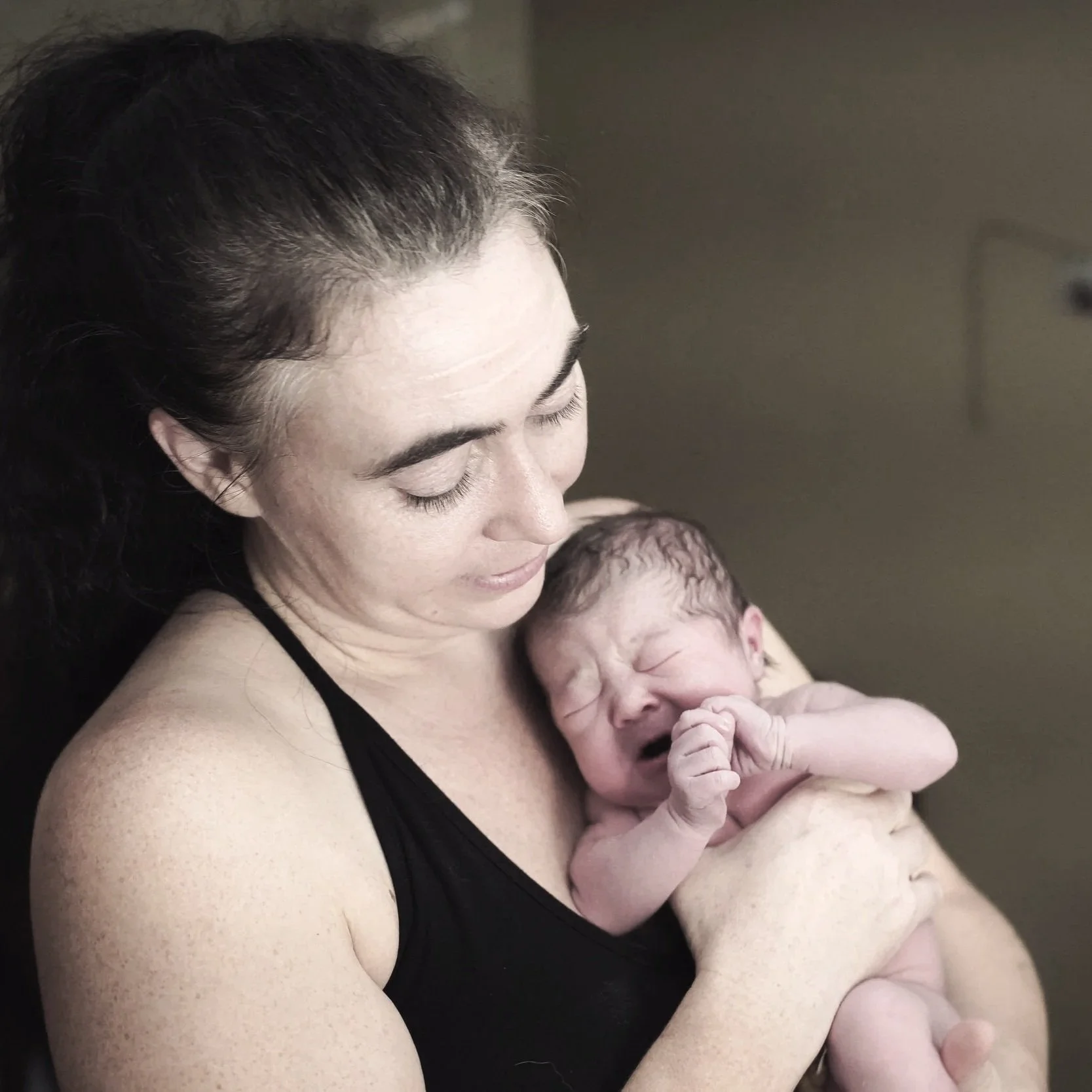 Veege Ruediger looks down while holding a newly born infant