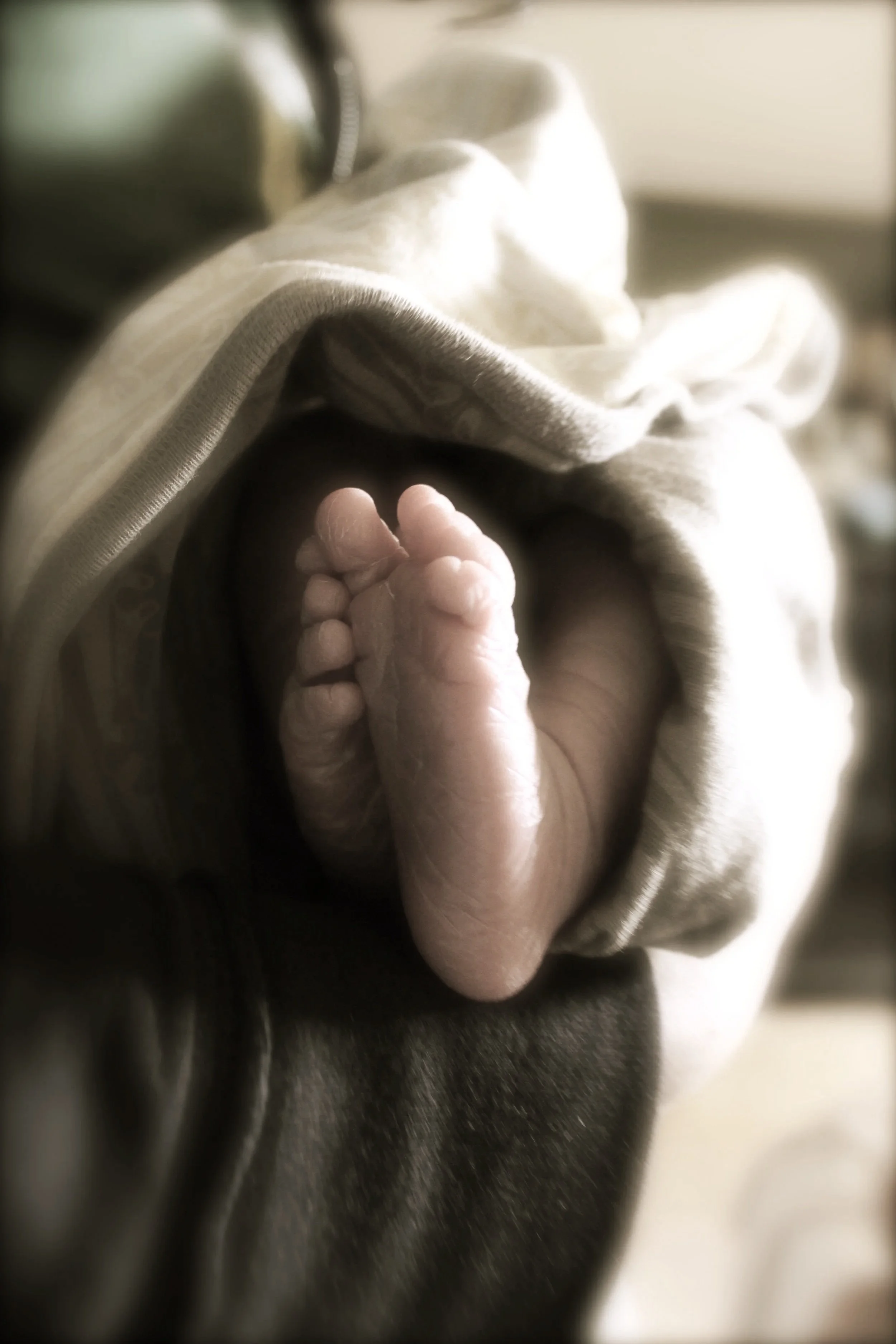 An infants feet stick out from a swaddled blanket