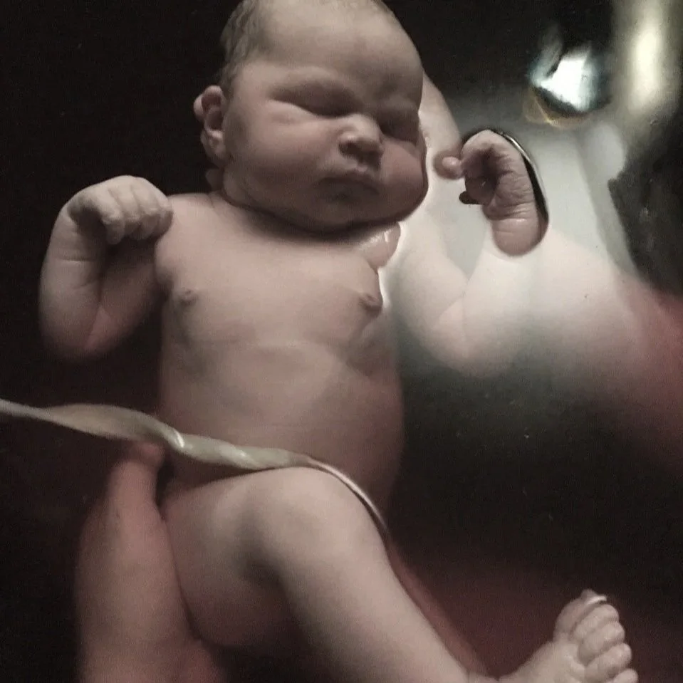 A newborn infant is held in water of a birth pool shortly after birth