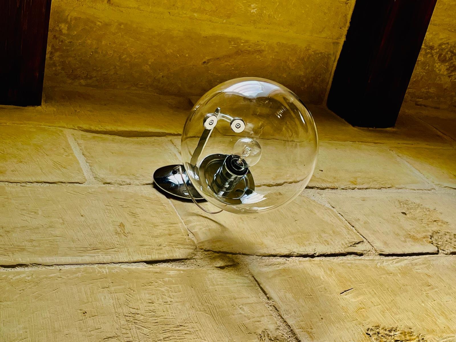 A lightbulb with a visible filament and a glass enclosure, lying on a wooden surface.