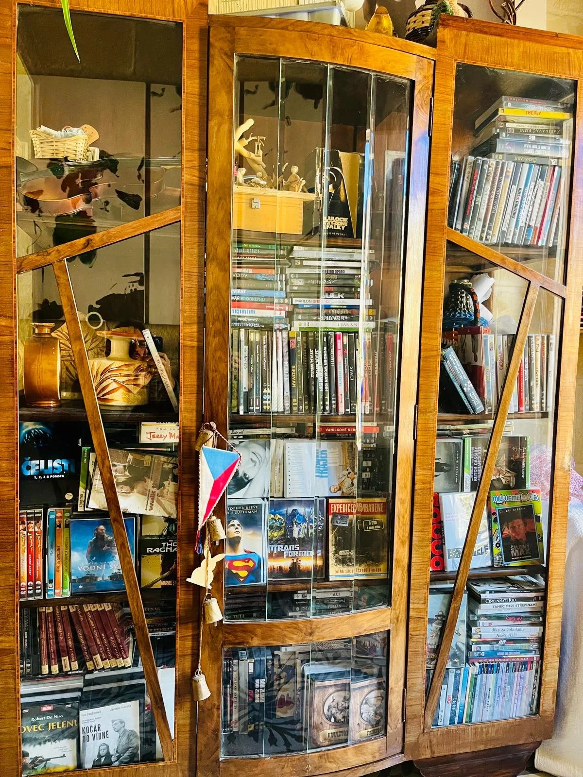 A wooden display cabinet filled with DVDs, CDs, and collectibles.