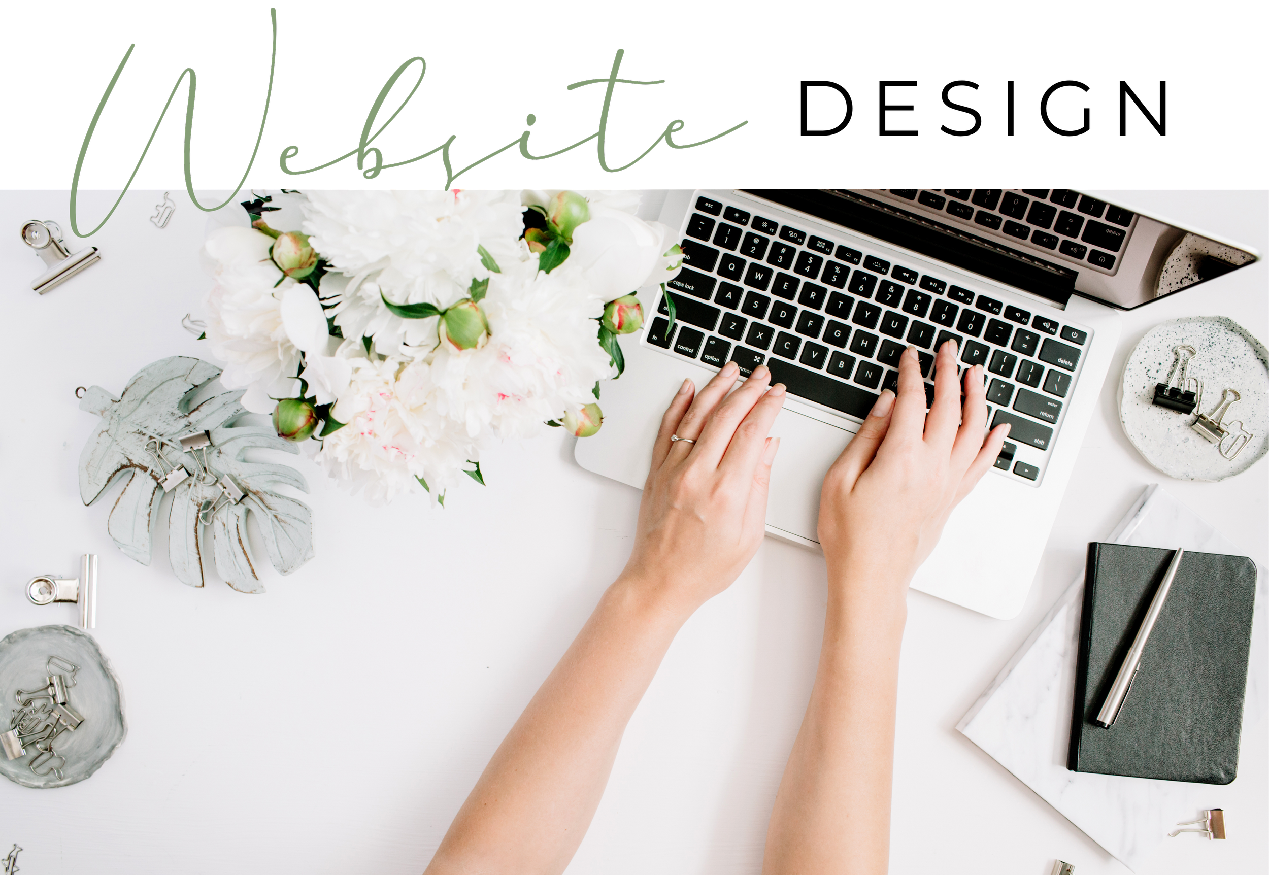 A person typing on a laptop keyboard at a white desk, with a bouquet of white flowers, plates with binder clips, a closed notebook, a pen, and other office supplies around.