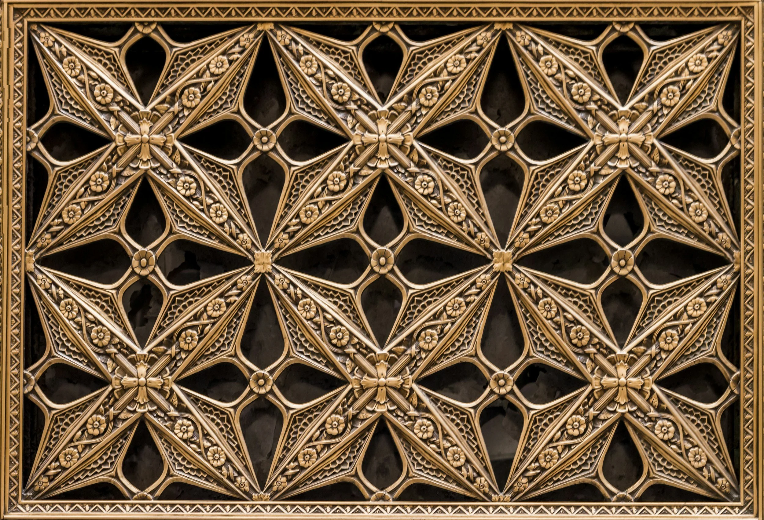 Intricate wooden lattice panel with geometric and floral patterns, framed with carved border.