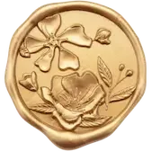 A decorative gold-colored coin featuring floral and botanical engravings including a bow, a flower, and leaves.