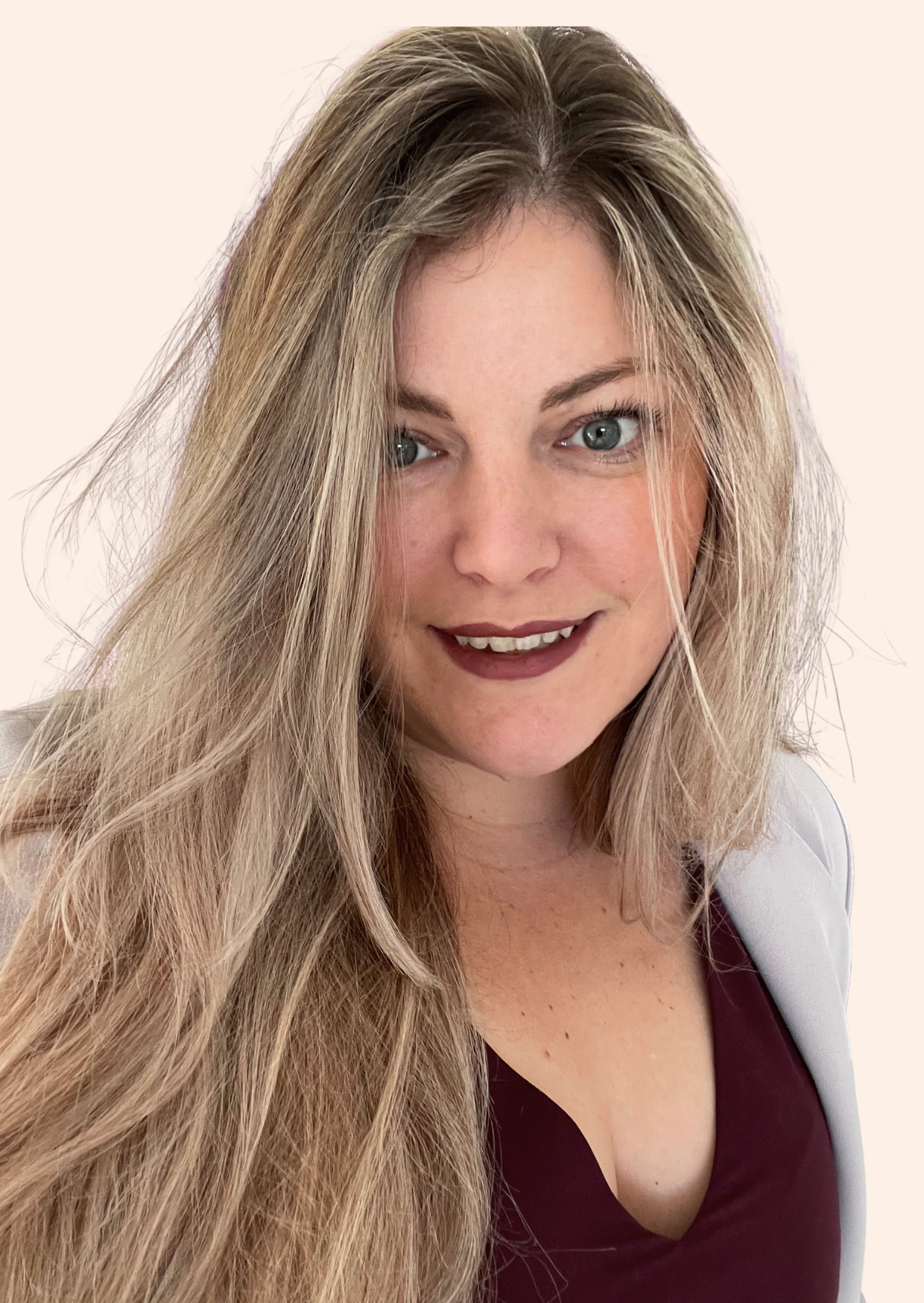 Headshot of Jo Pope. Long blonde hair, blue eyes, smiling at the camera, wearing a maroon top and a light-colored blazer, against a plain background.