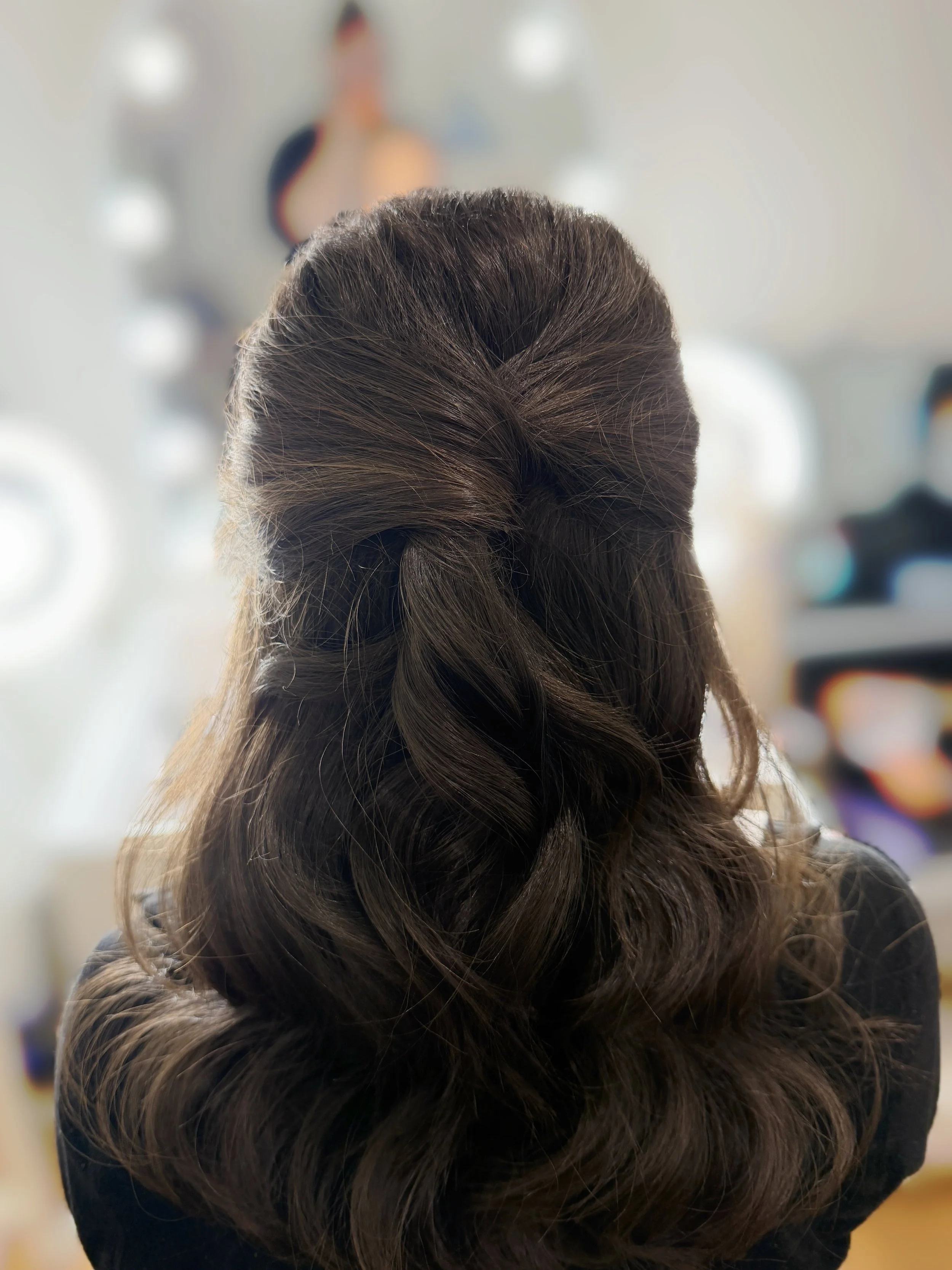 The back of a woman's head with long, wavy brown hair styled in an elegant twisted updo.