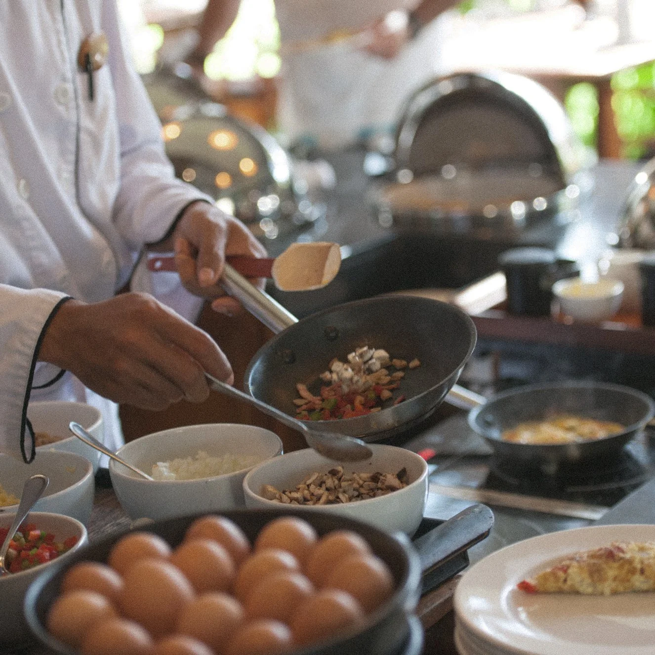 Chef’s hands sautéing fresh ingredients in a pan over a stove