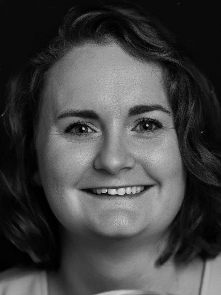 Black and white portrait of a smiling woman with wavy hair.