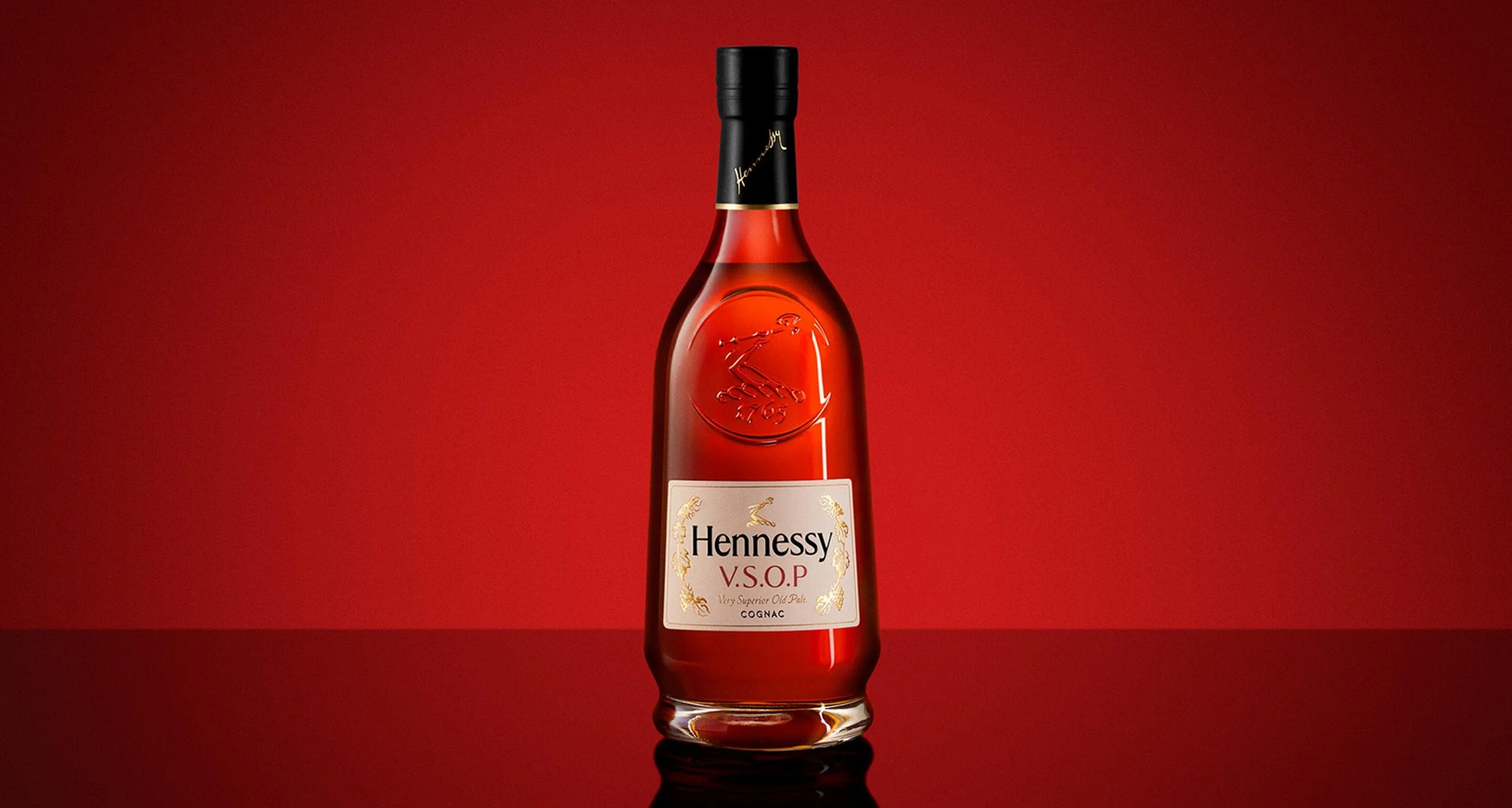 A bottle of Hennessy V.S.O.P cognac with a black cap and white label, set against a red gradient background.