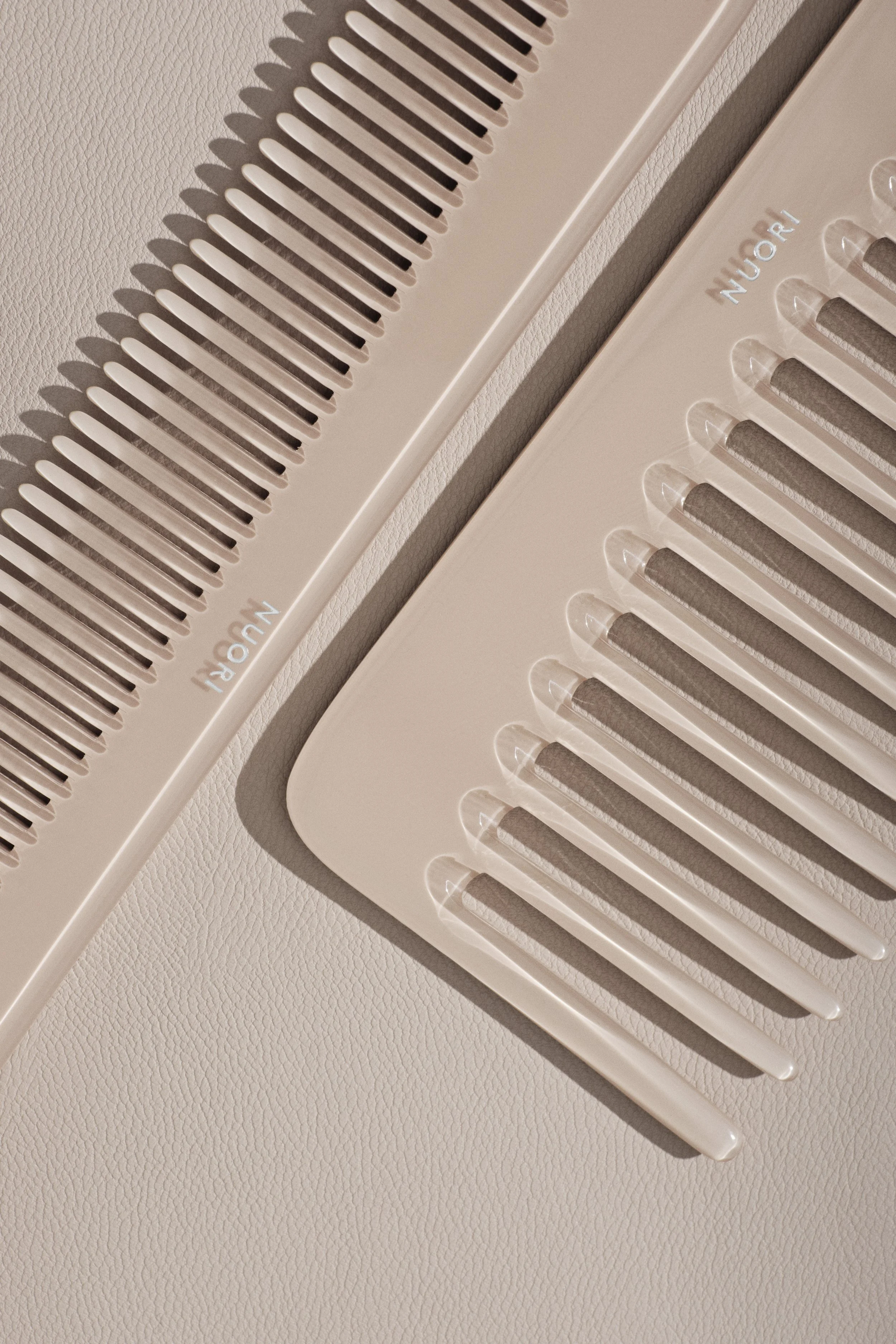 Close-up of two white air vents on a ceiling, with one vent showing the brand name 'NUORI' and casting shadows on the textured ceiling surface.