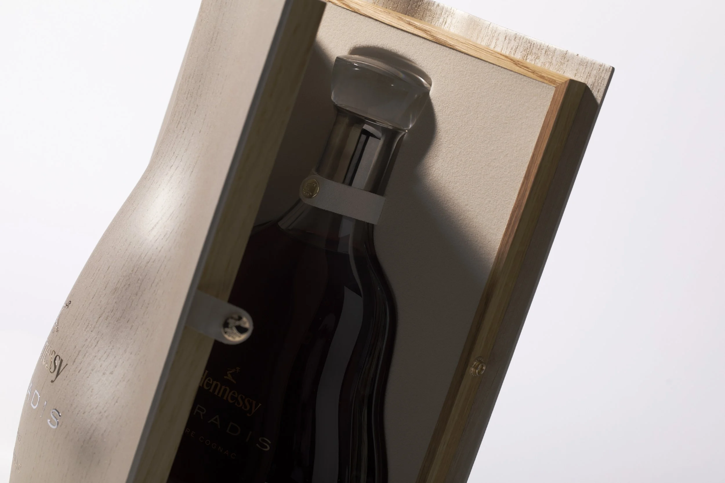 A bottle of Hennessy X.O Cognac inside a wooden display box with a glass front door.