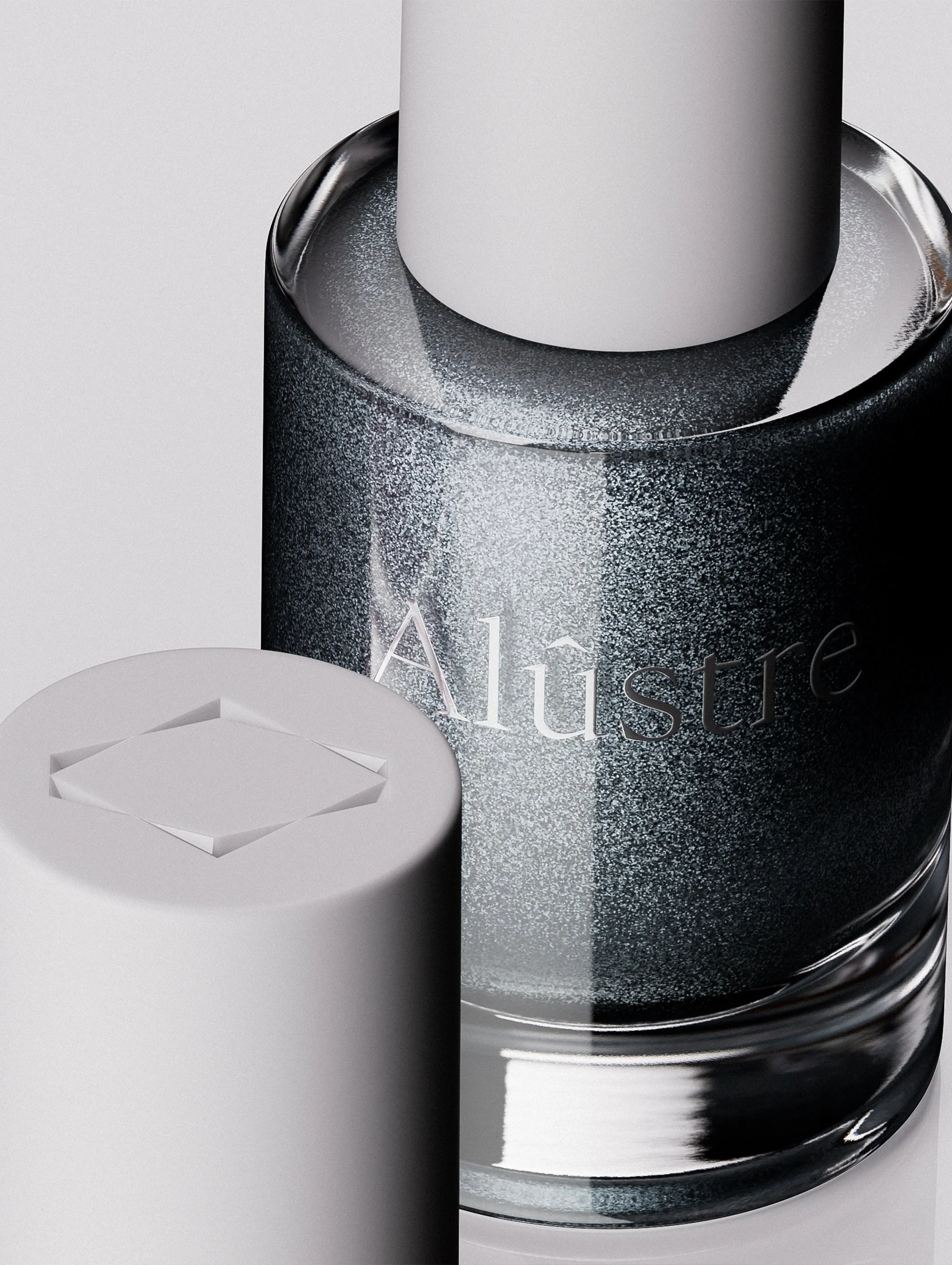 Close-up of a bottle of Alustre skincare product with a gray cap and a black and silver textured container next to it.