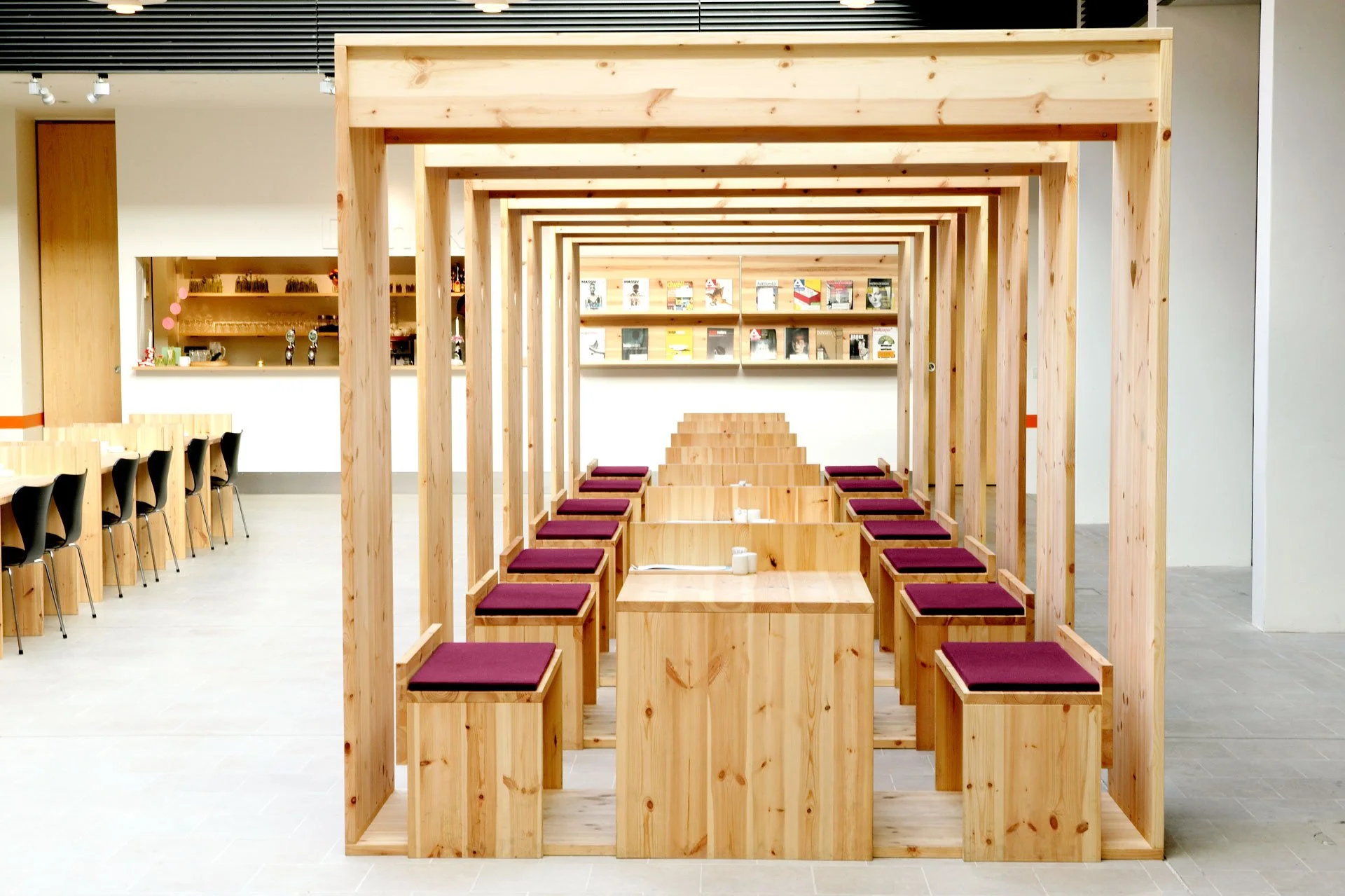 Empty wooden seating area with purple cushions in a modern cafe or restaurant.