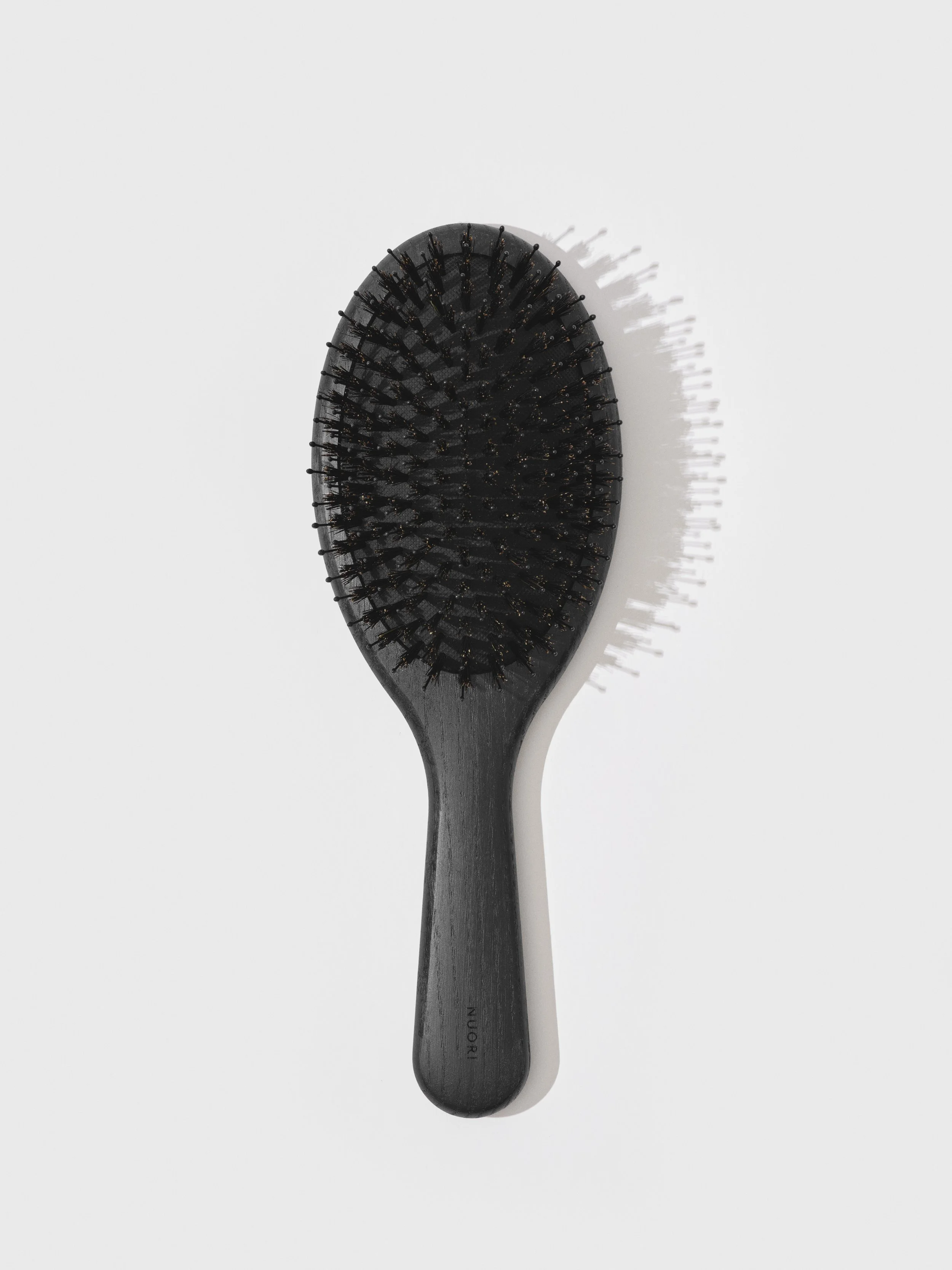A black hairbrush with fine bristles on a plain white background.